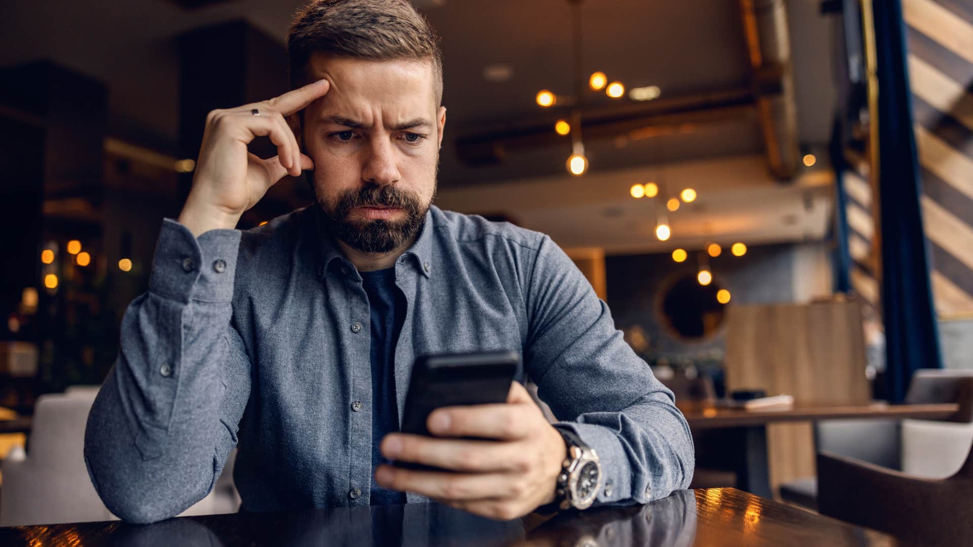 Worried man staring at his phone.