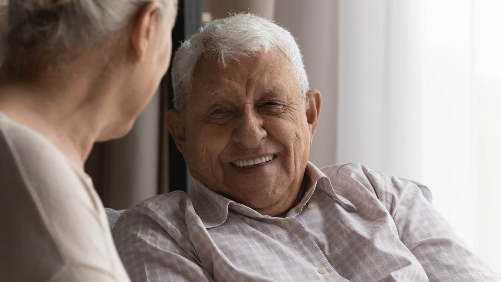 Older man smiling and talking to a woman.