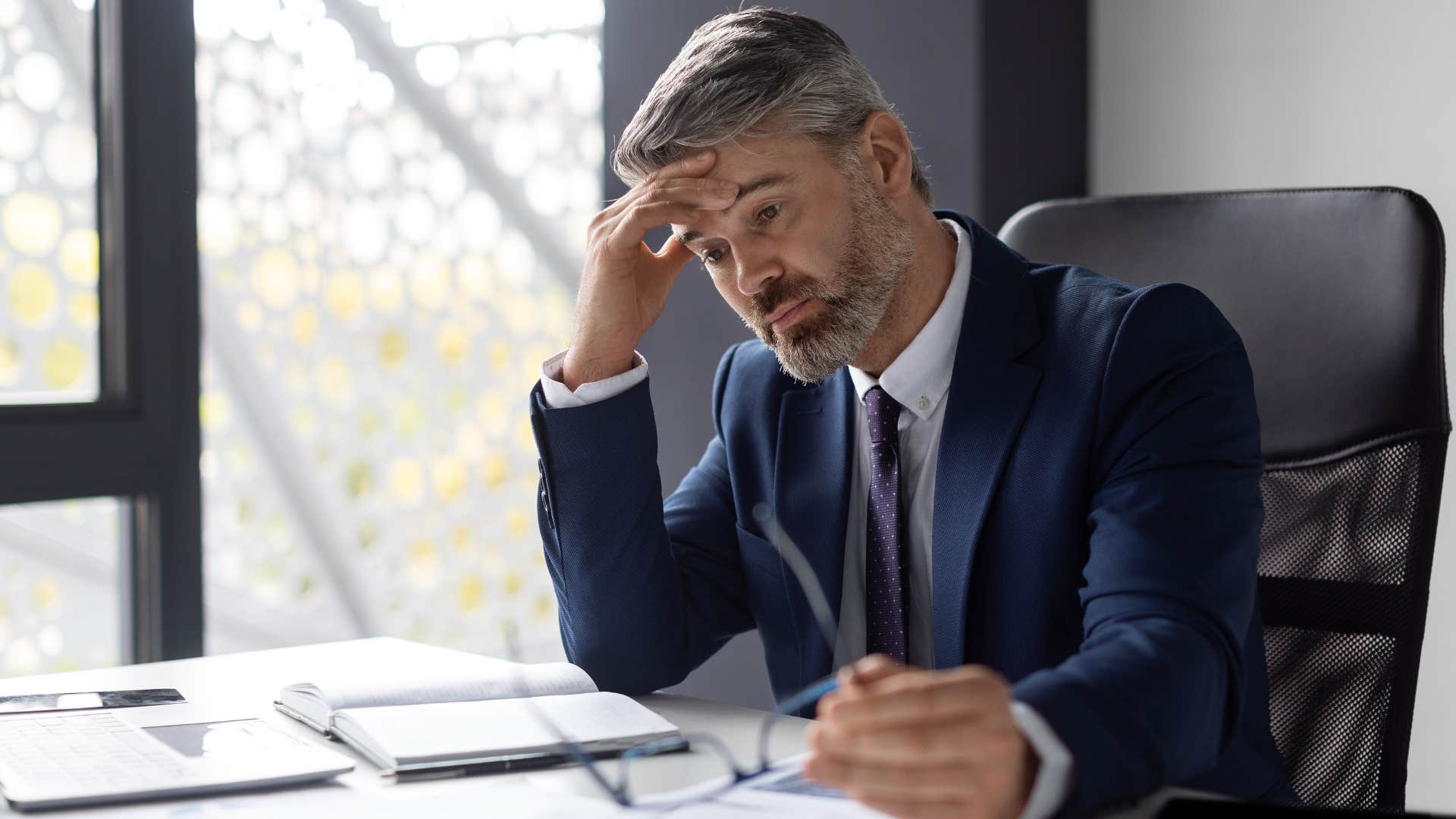 Gen X man tired holding his head at work