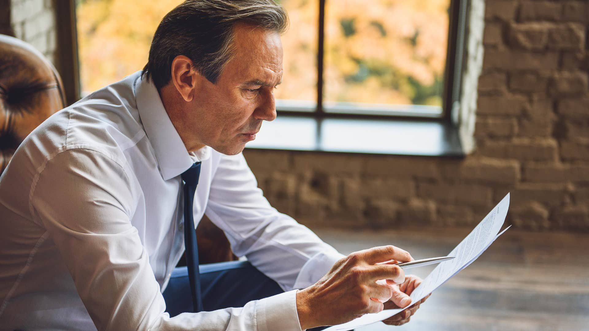 Gen X man looking at a piece of a paper at work