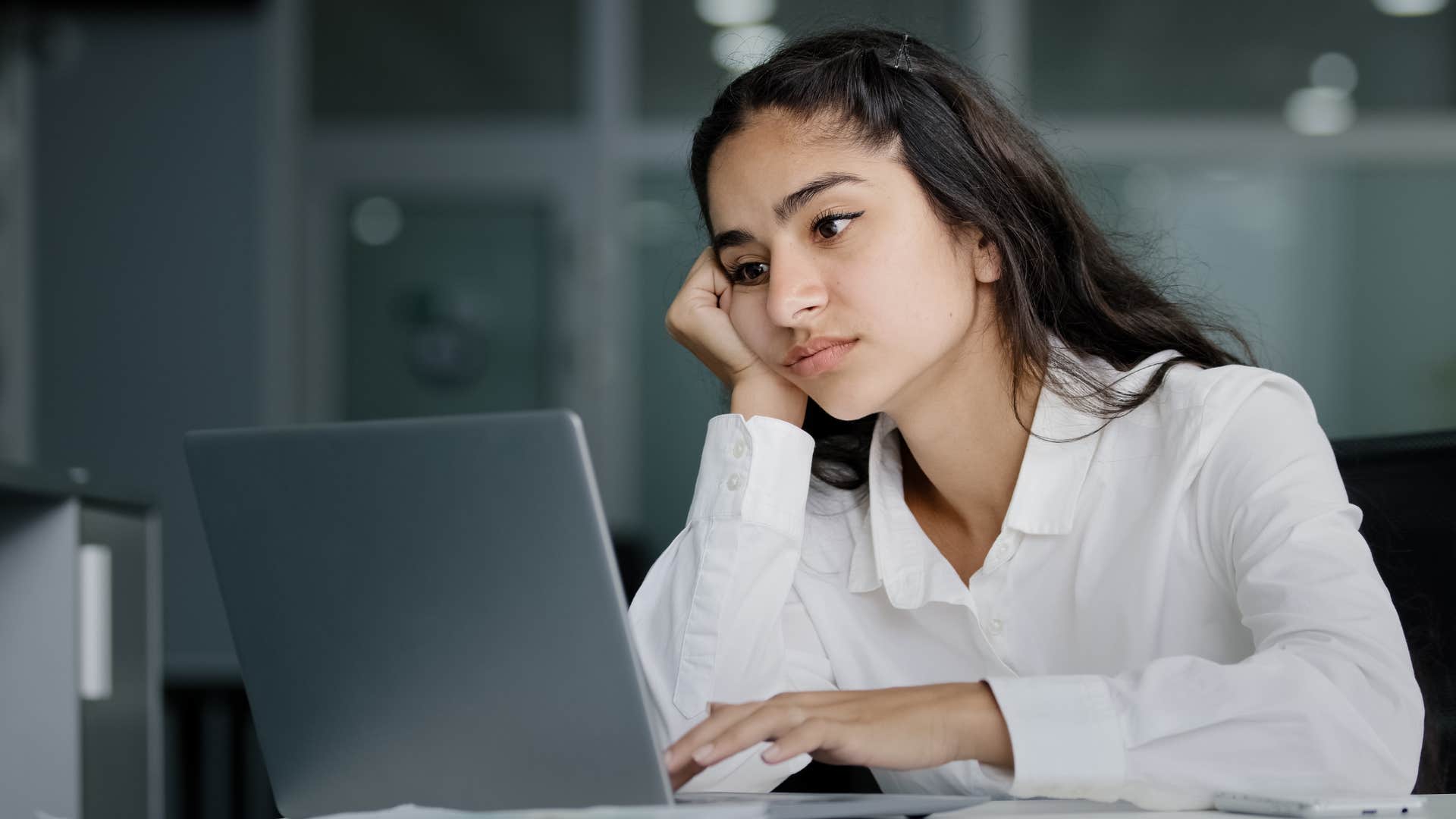 Gen Z worker looking annoyed working on her laptop