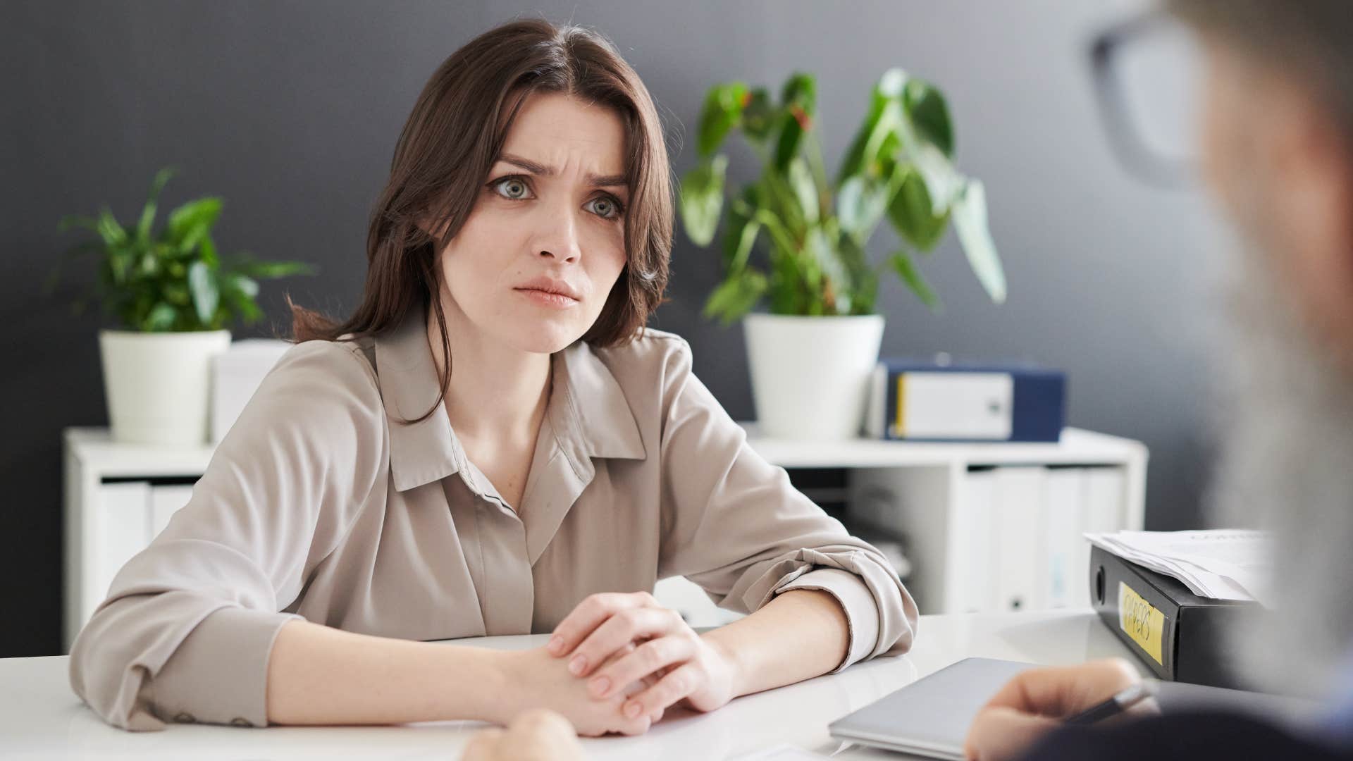 Woman looking shocked talking to her boss at work