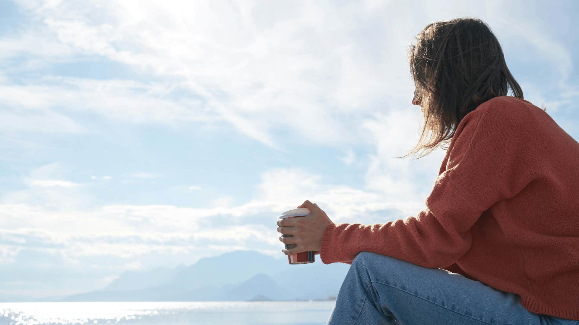 woman with coffee looking out at water