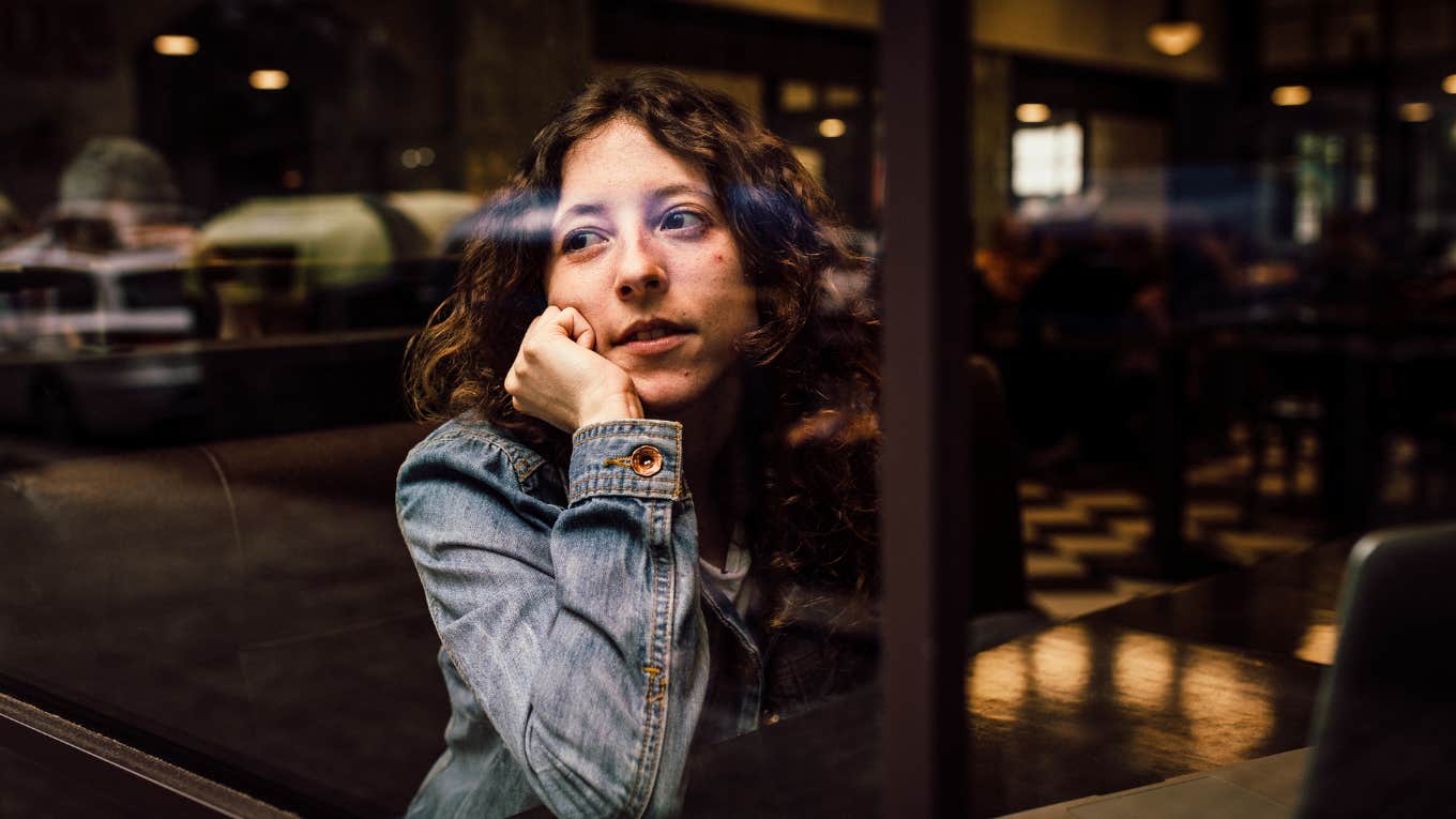 Woman looking somberly out window