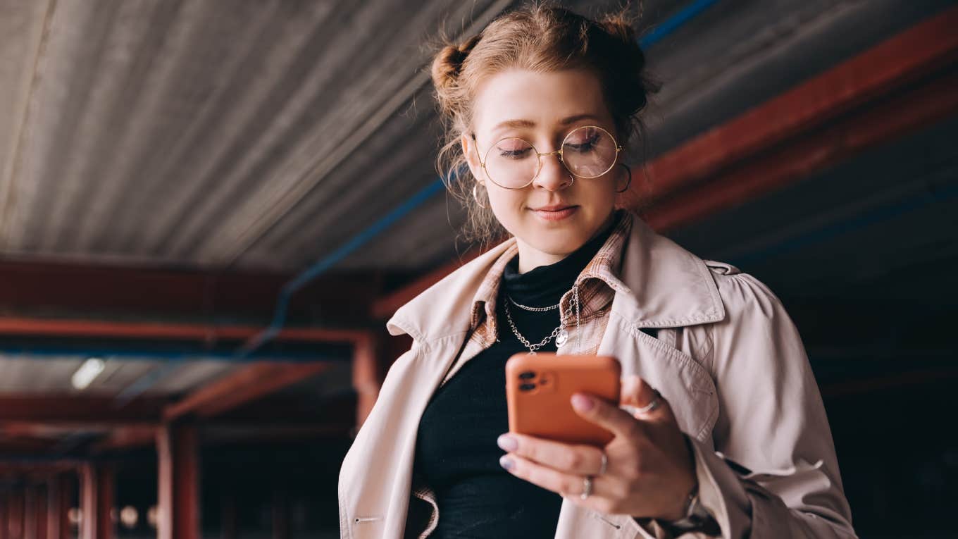 young woman looking at phone in parking lot