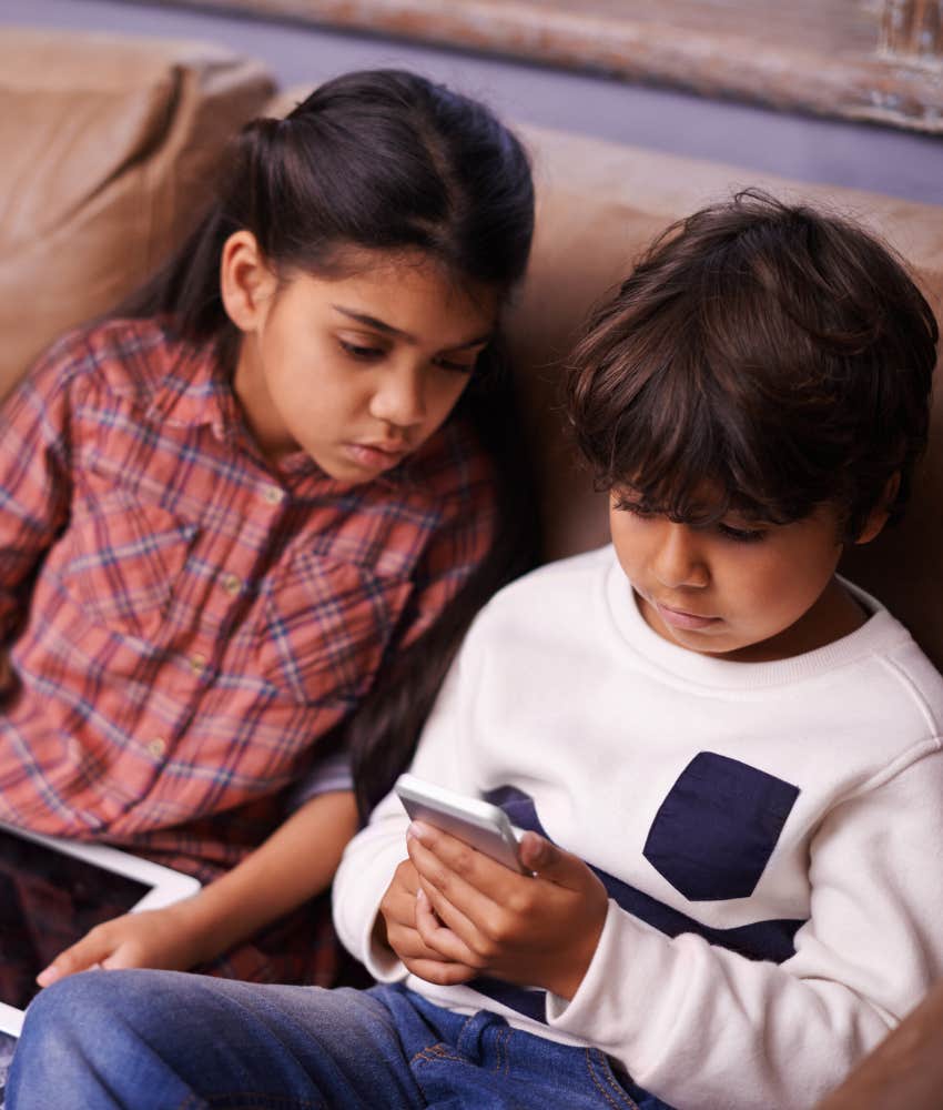 little girl and boy sitting on couch staring at screens