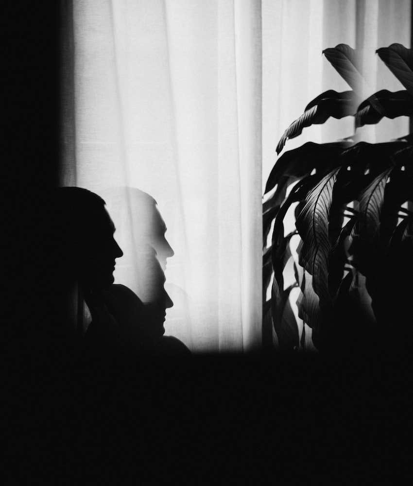 Shadow profile of person sitting at curtained window