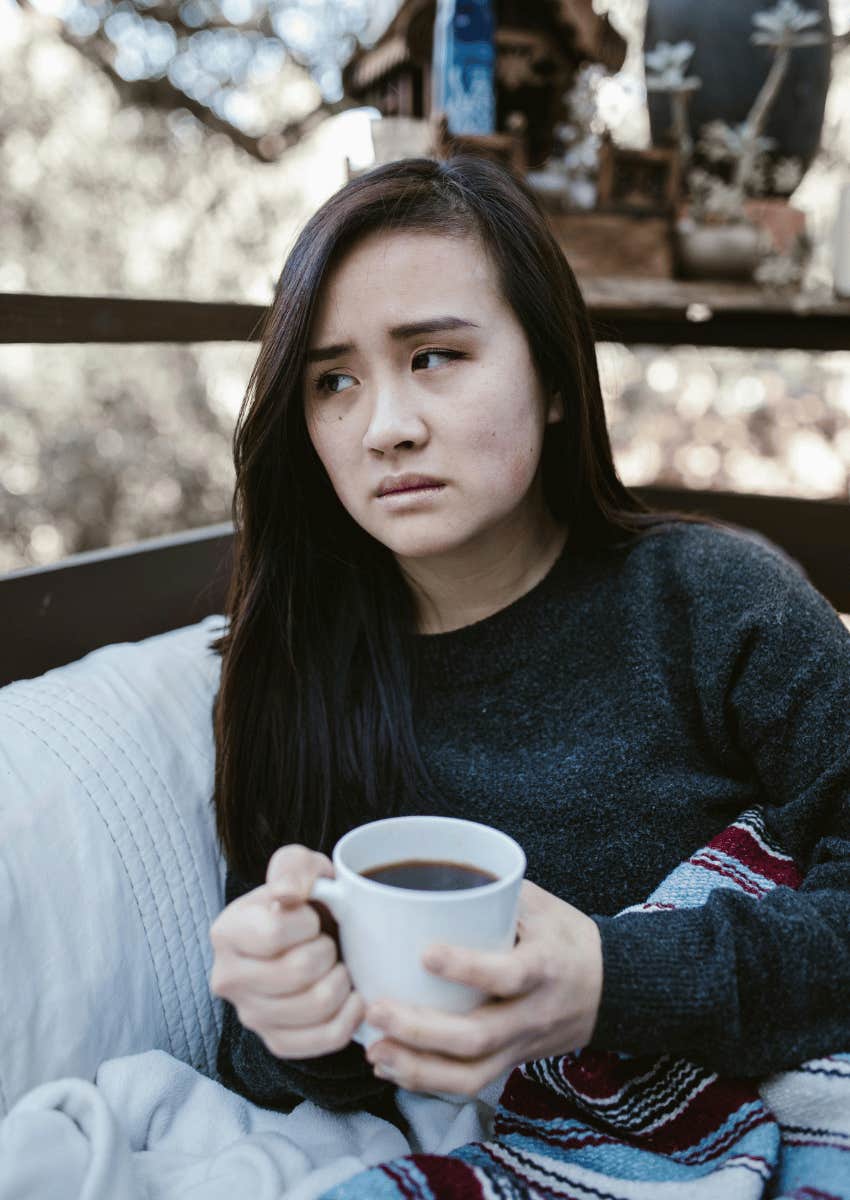 serious woman holding a mug while sitting outdoors