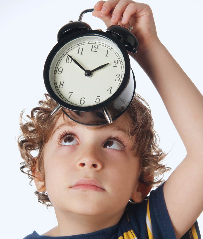 little boy holding analog clock