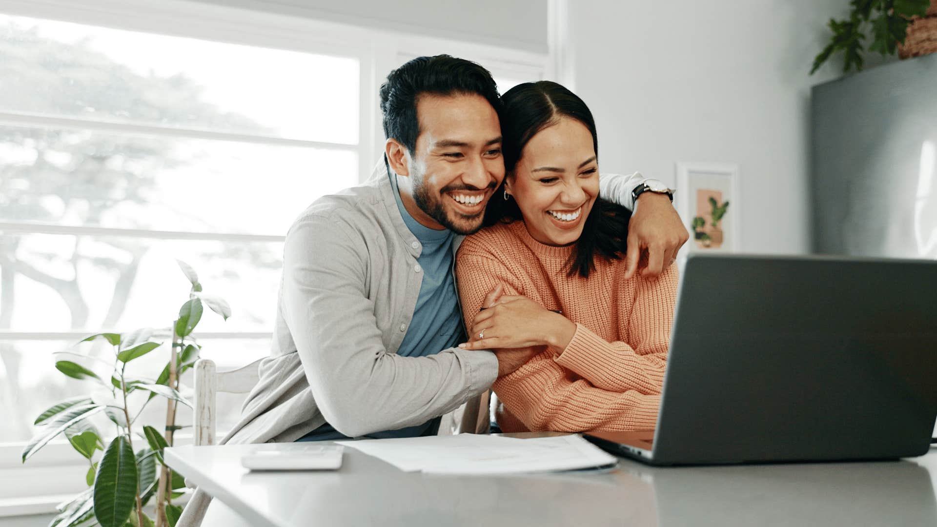 Affection couple cuddles while looking at computer