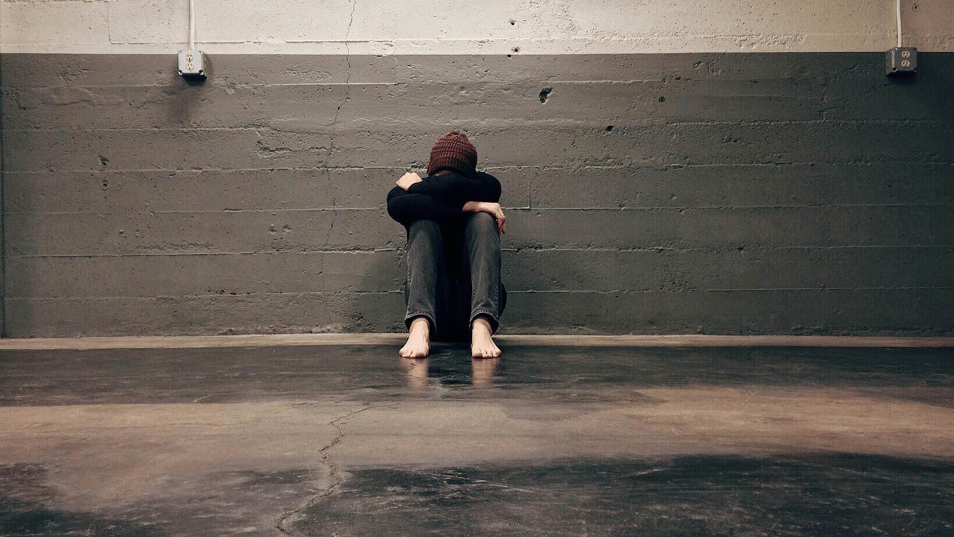 man sitting alone with his head in his lap