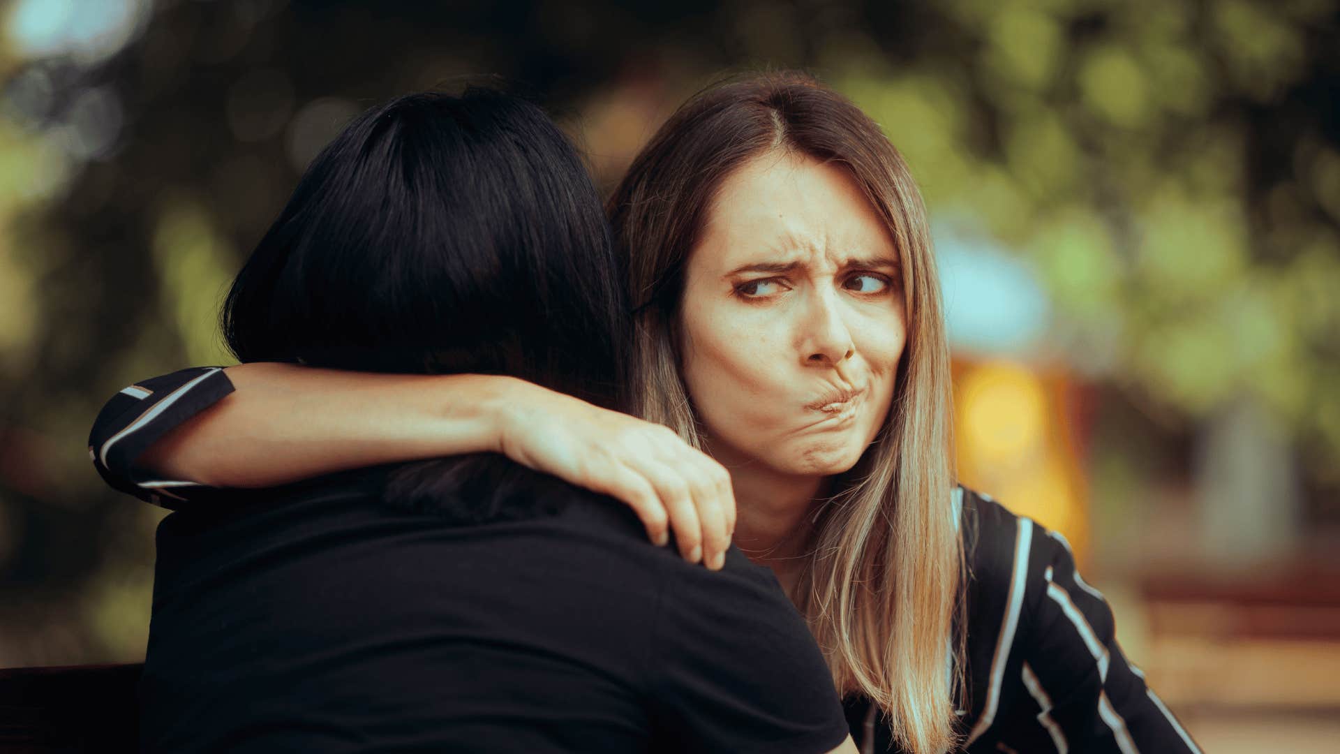 woman making face behind friend's back