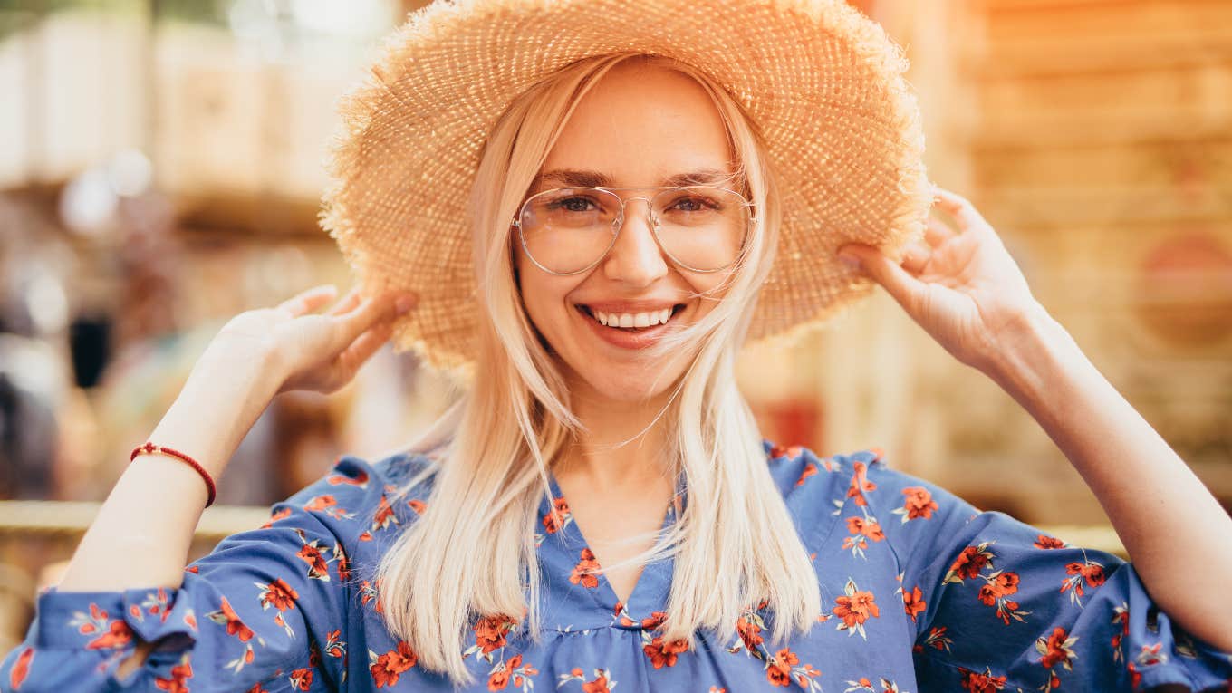 confident woman holding wide brimmed hat