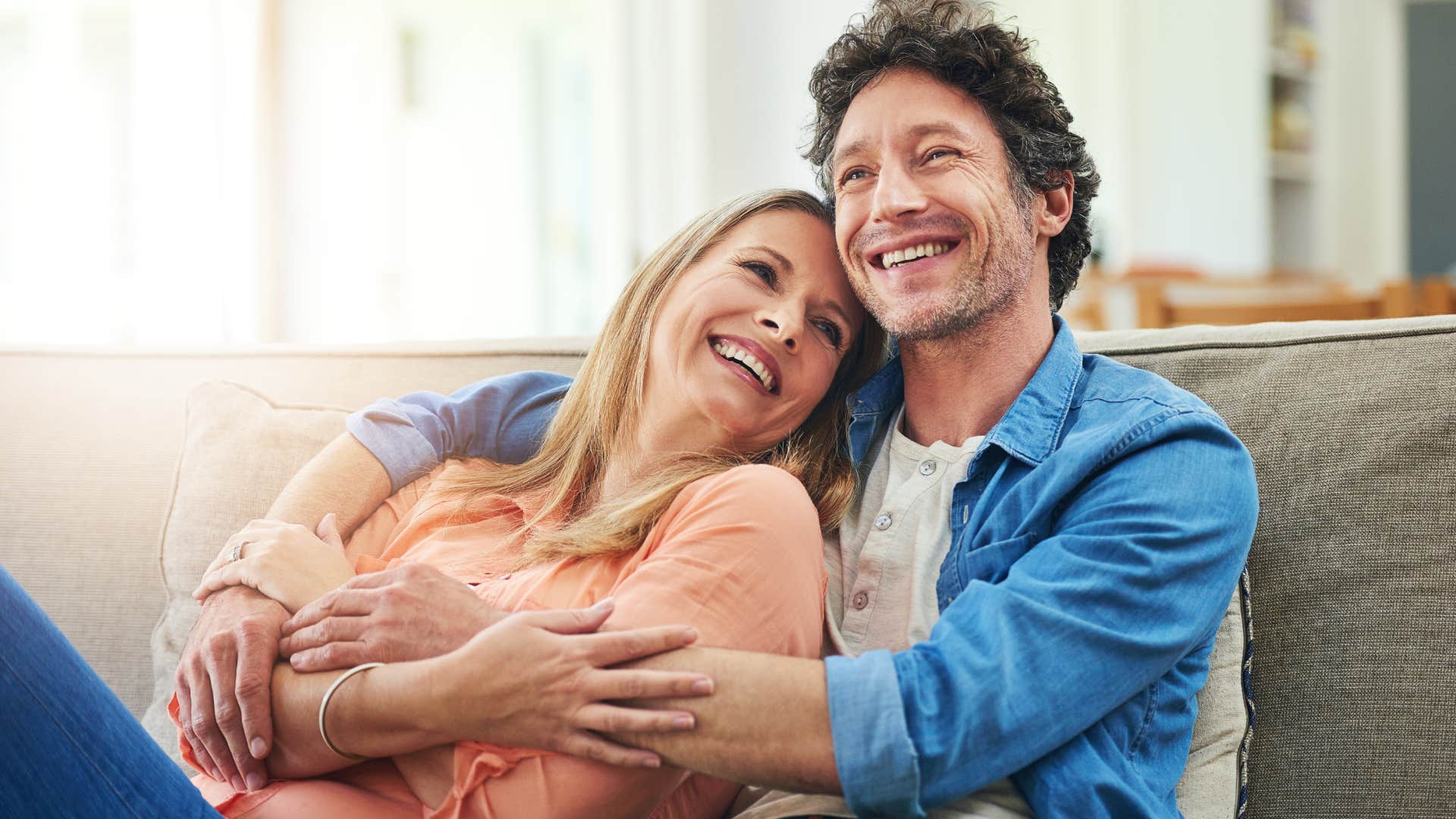 Couple smiling and hugging on the couch.