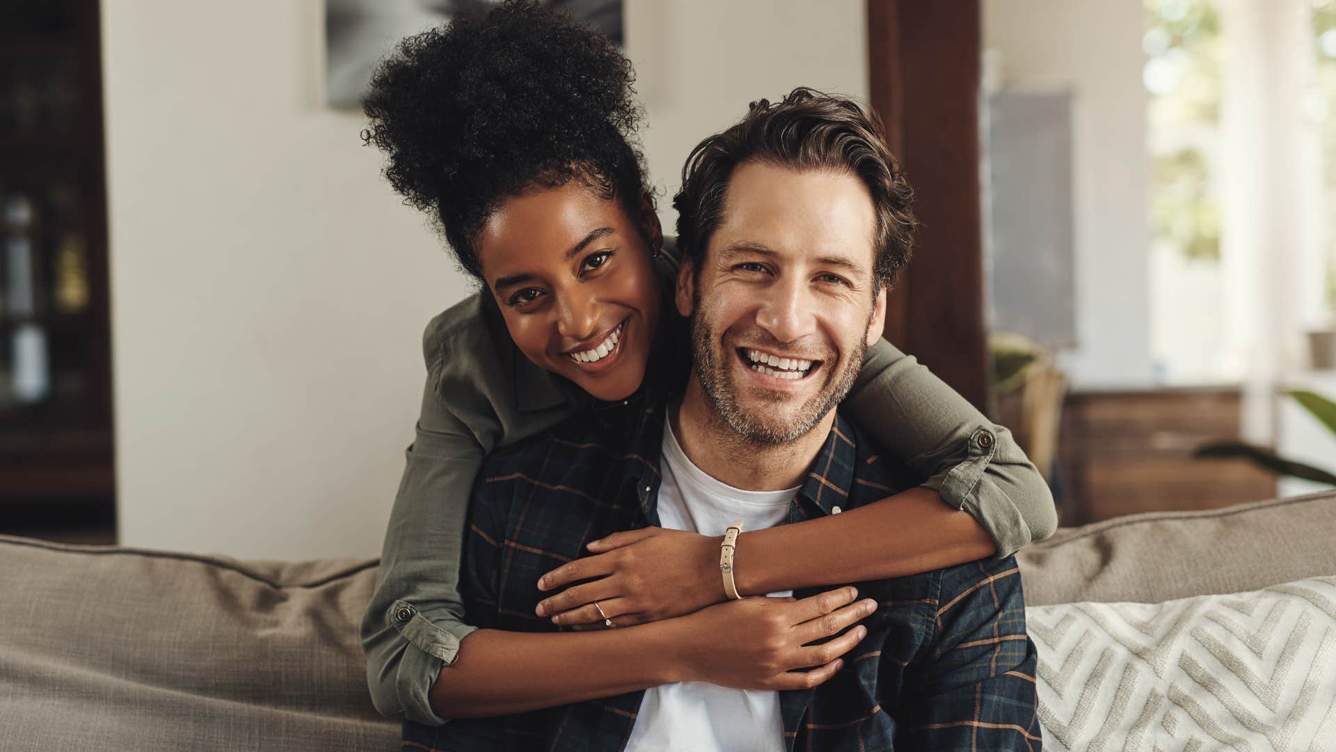 Woman hugging her husband on the couch.