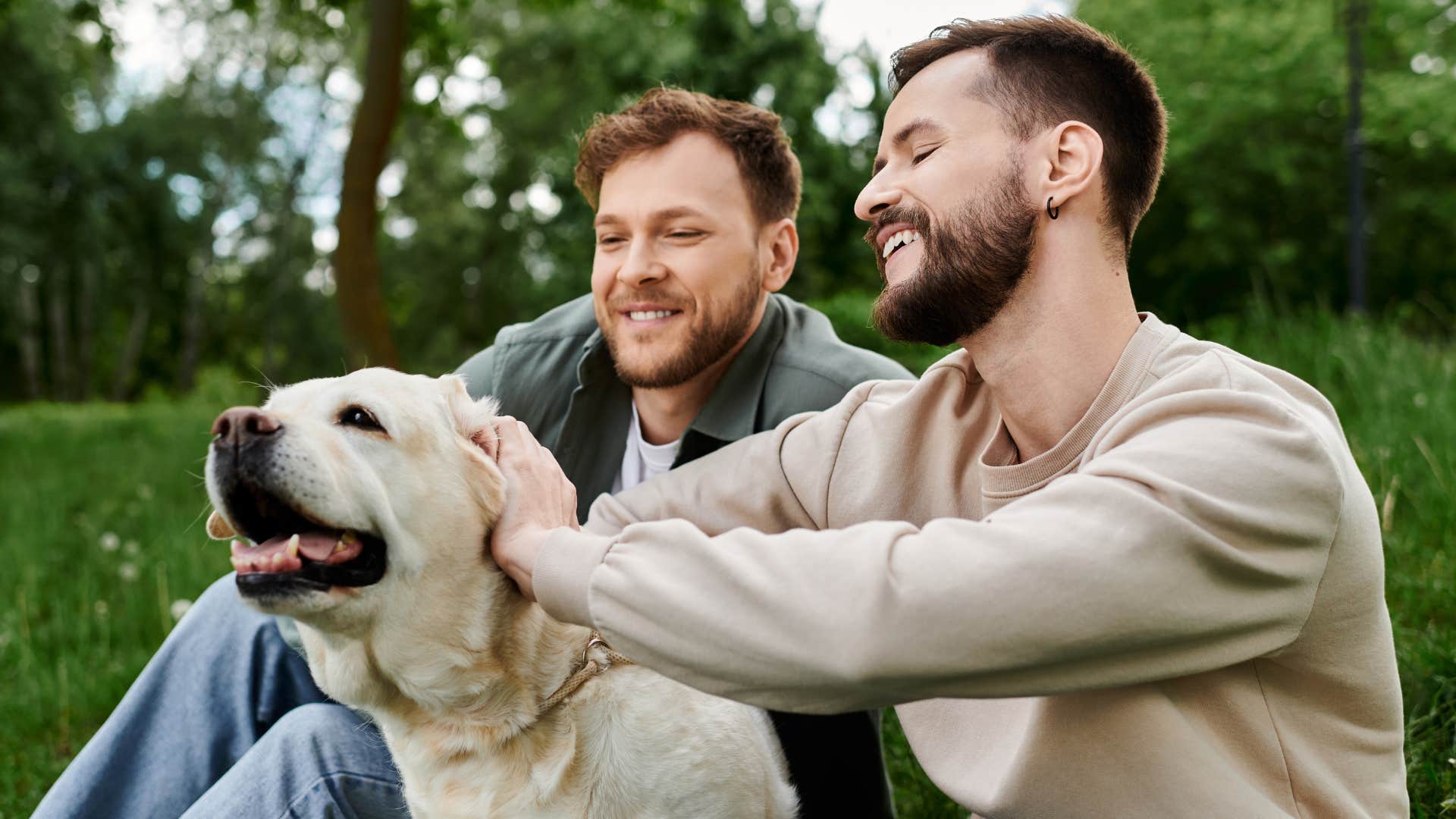 Couple smiling and petting a dog outside.