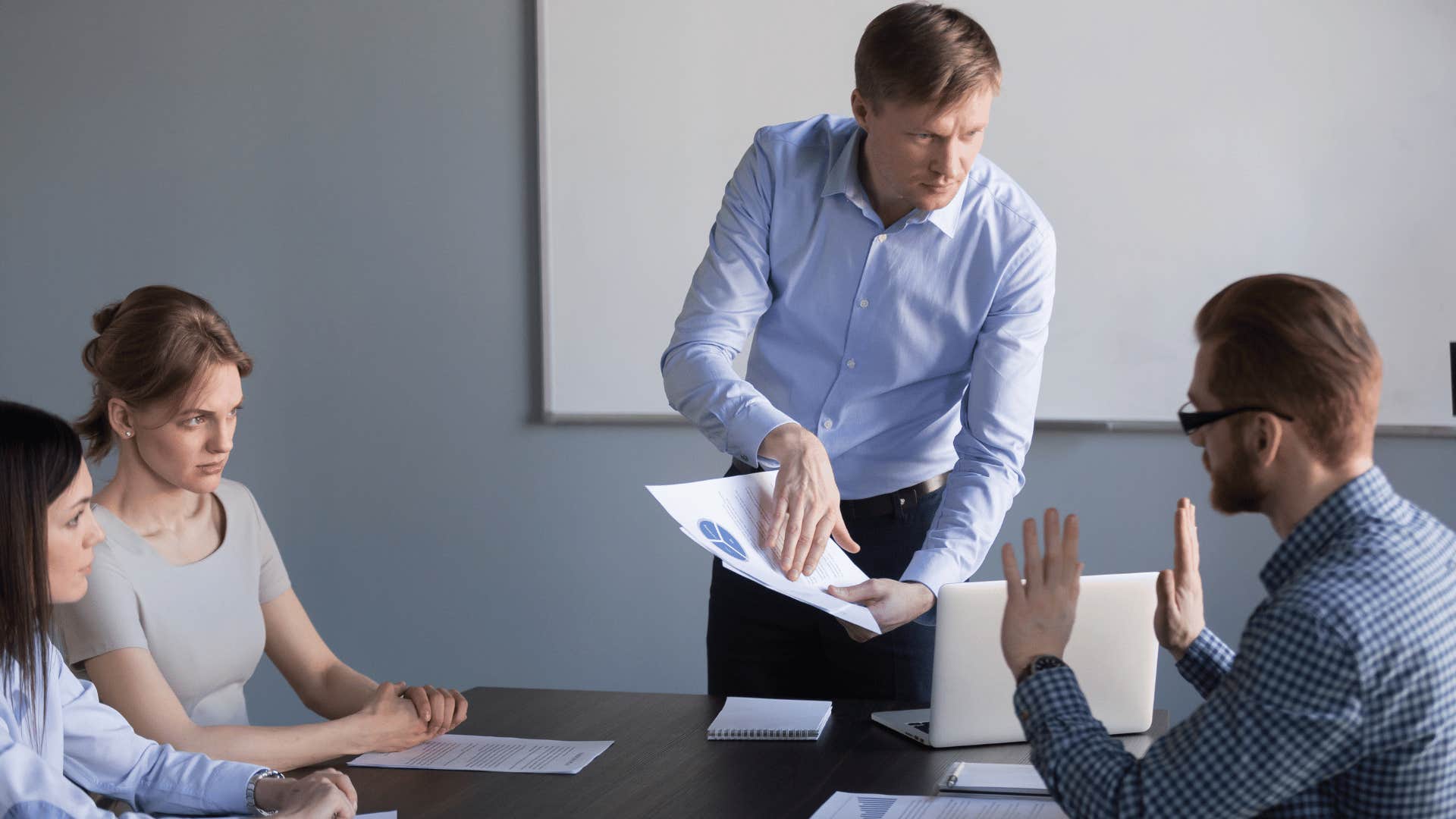 man frustrated and pointing at paper to coworker