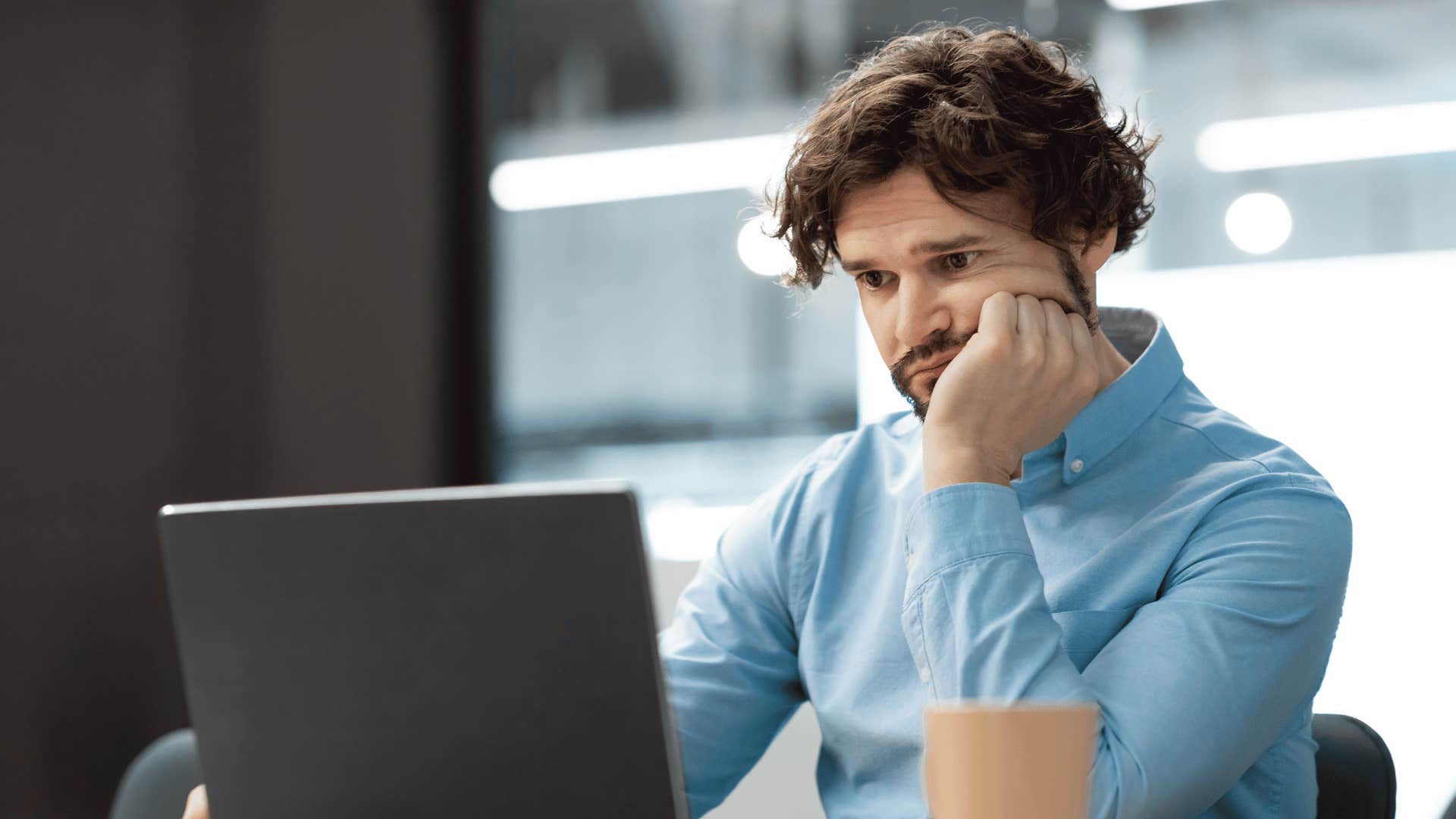 man looking at laptop with hand in head