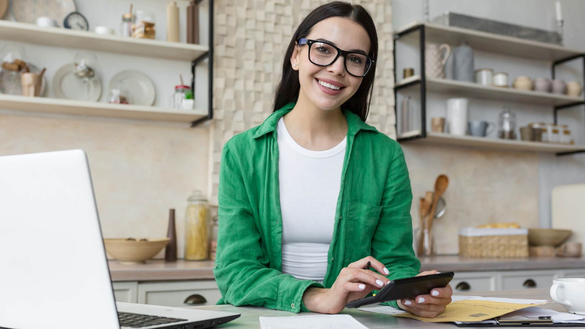 Woman smiling and doing bills on her laptop.