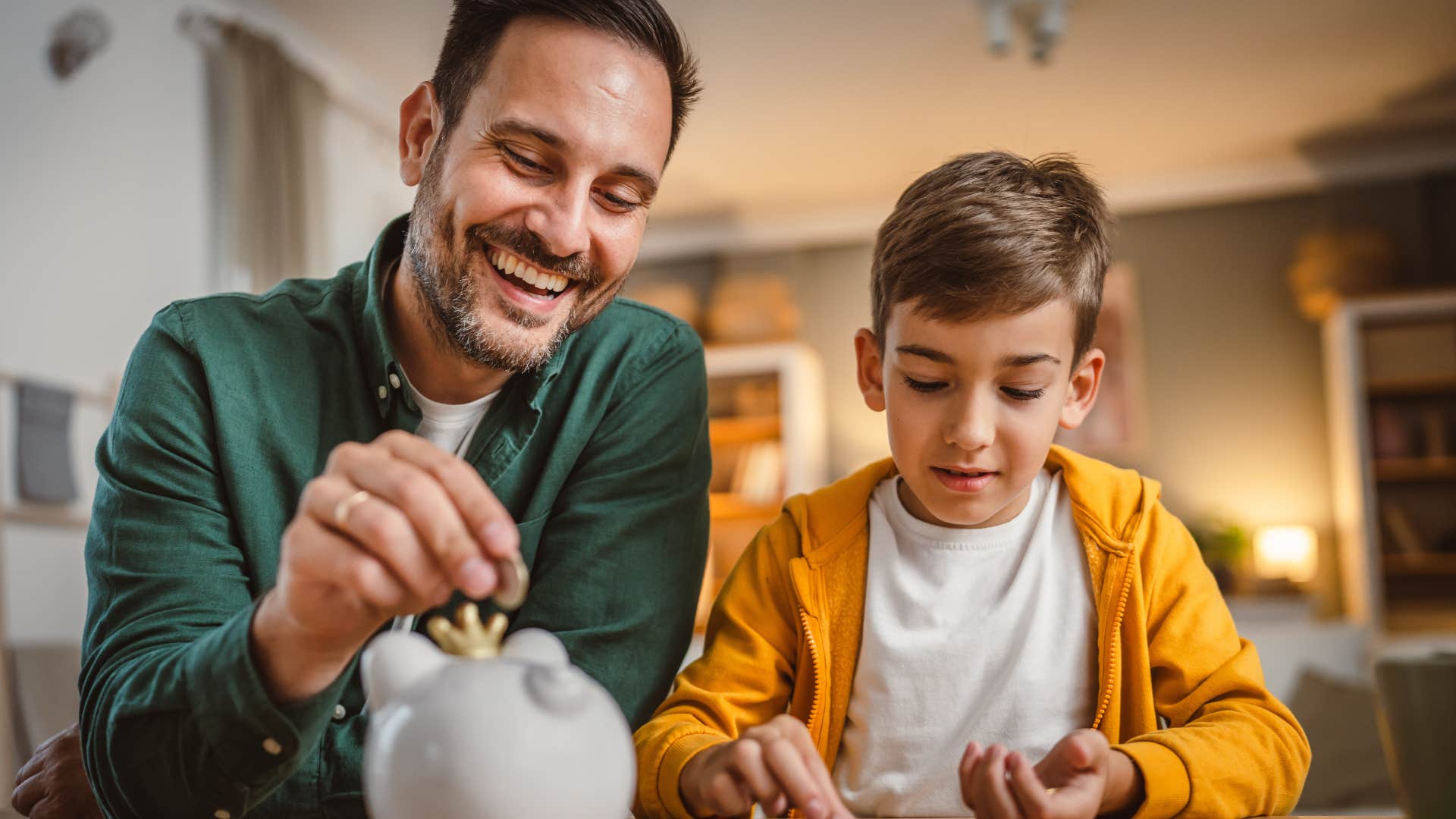 Man putting pennies into a piggy bank with his son.