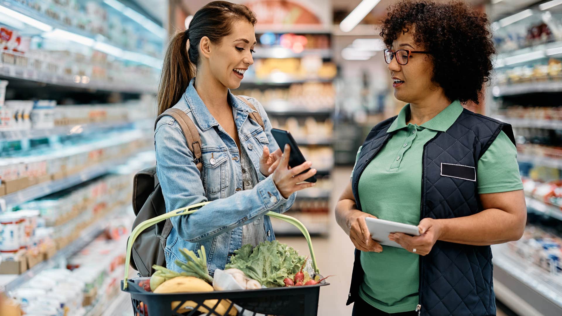 Woman showing a grocery store worker something on her phone.