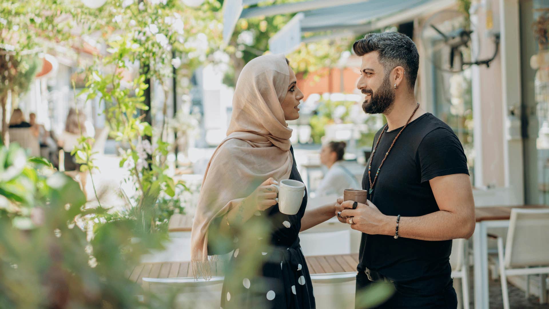 man and woman talking while holding coffee