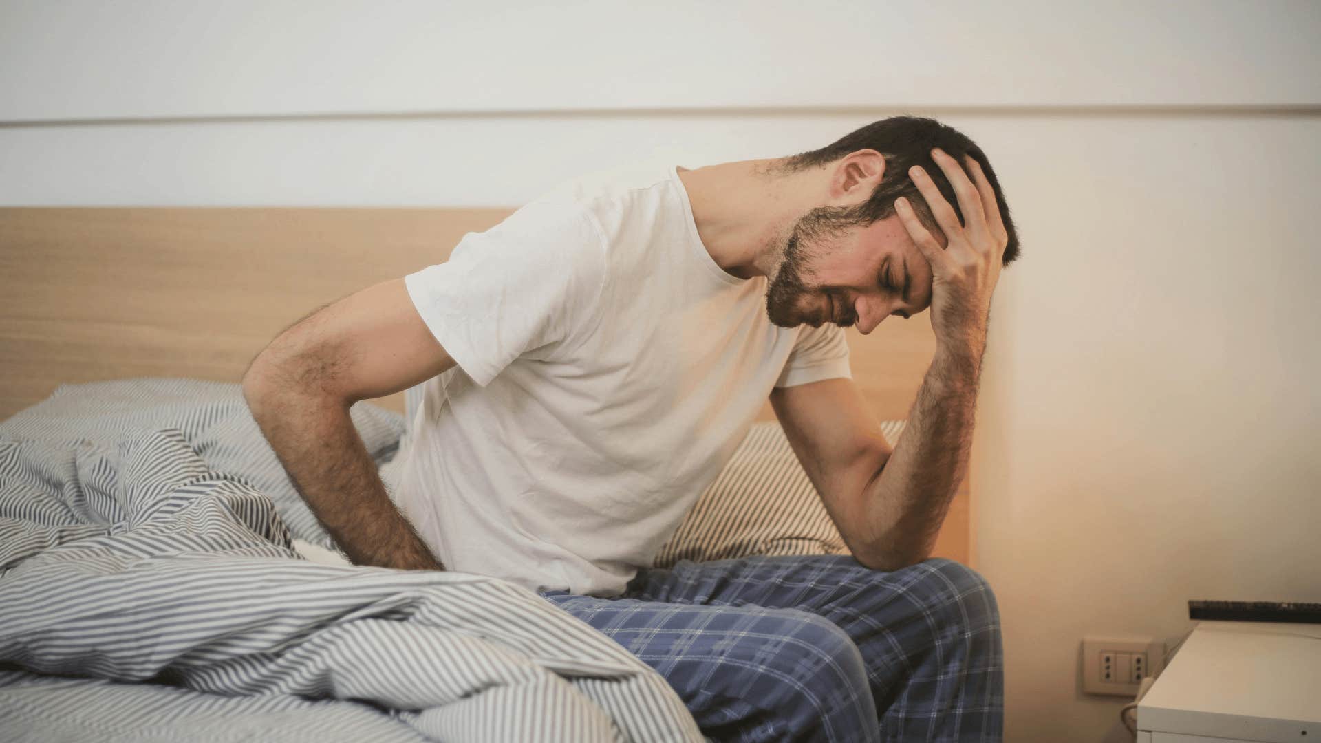 man with his head in his hand sitting in bed