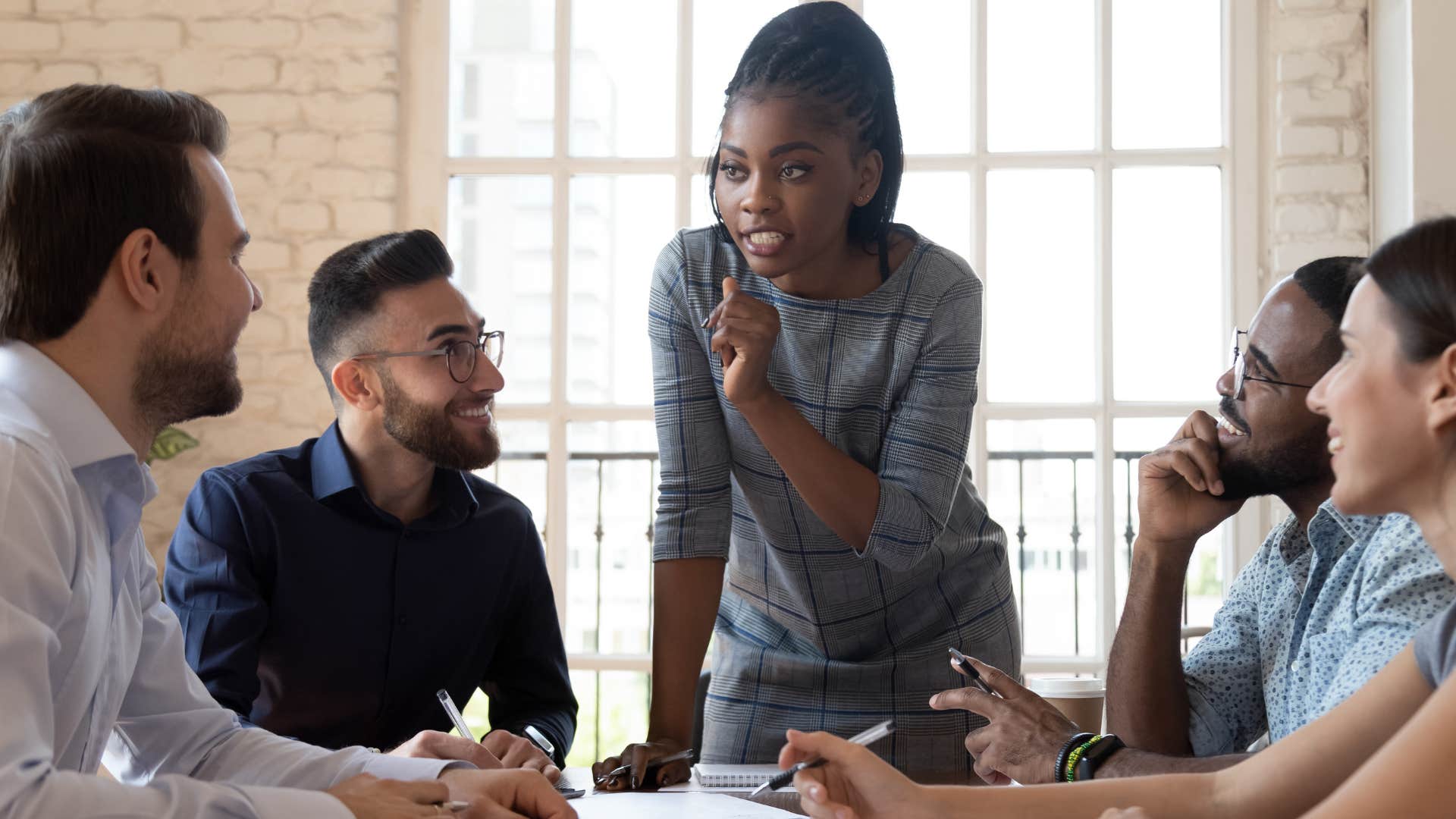 Woman standing in a work meeting talking to a peer.