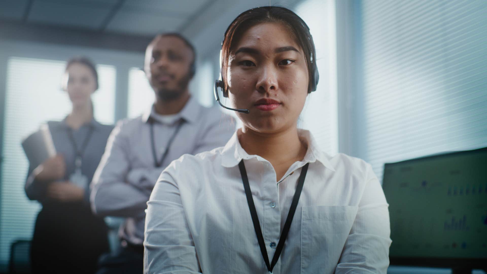 Worker looking upset with her bosses standing behind her.