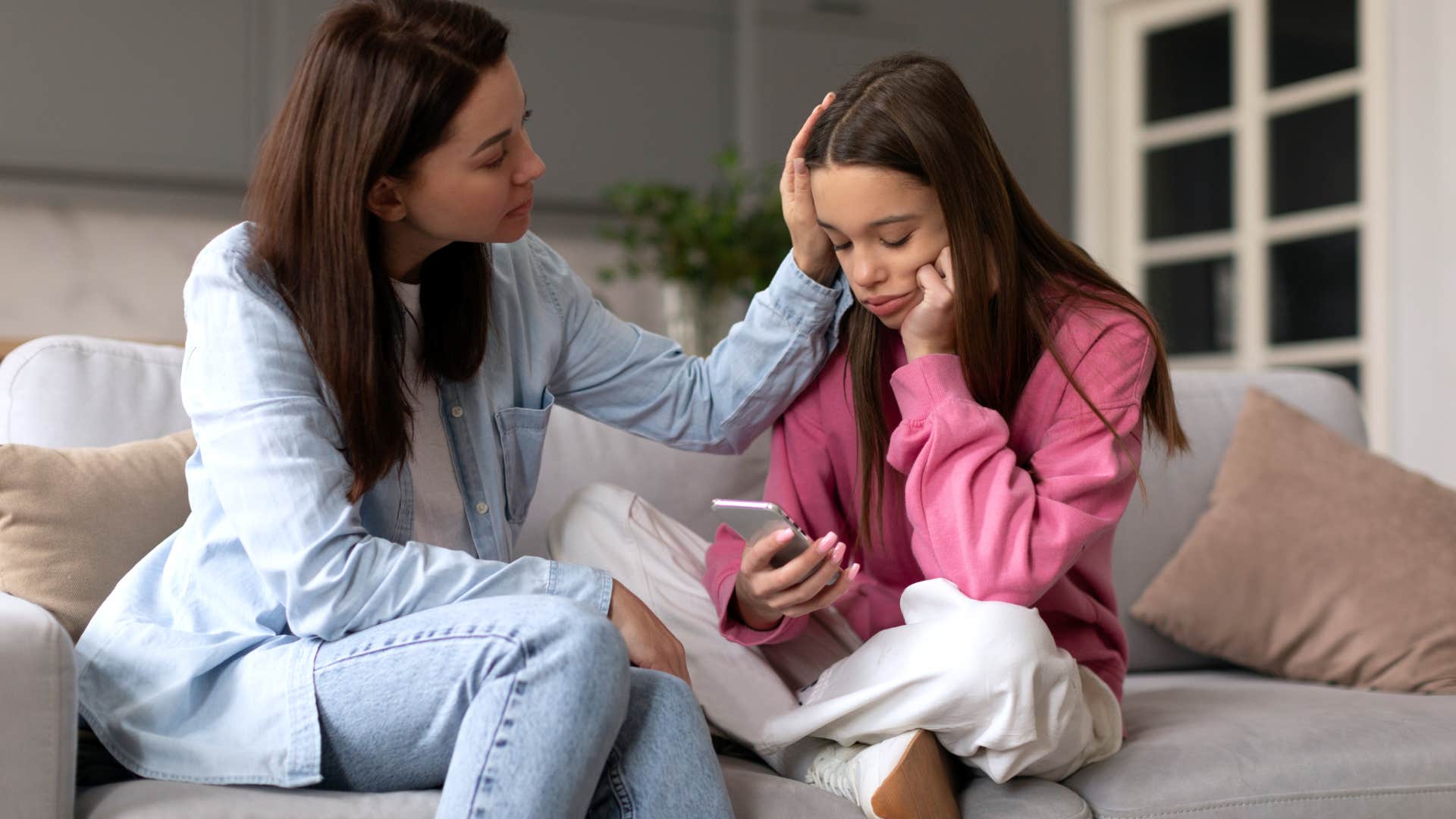 Woman comforting her teenage daughter on the couch.