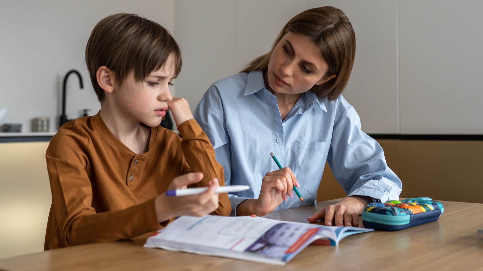 Woman helping her young son with his homework.