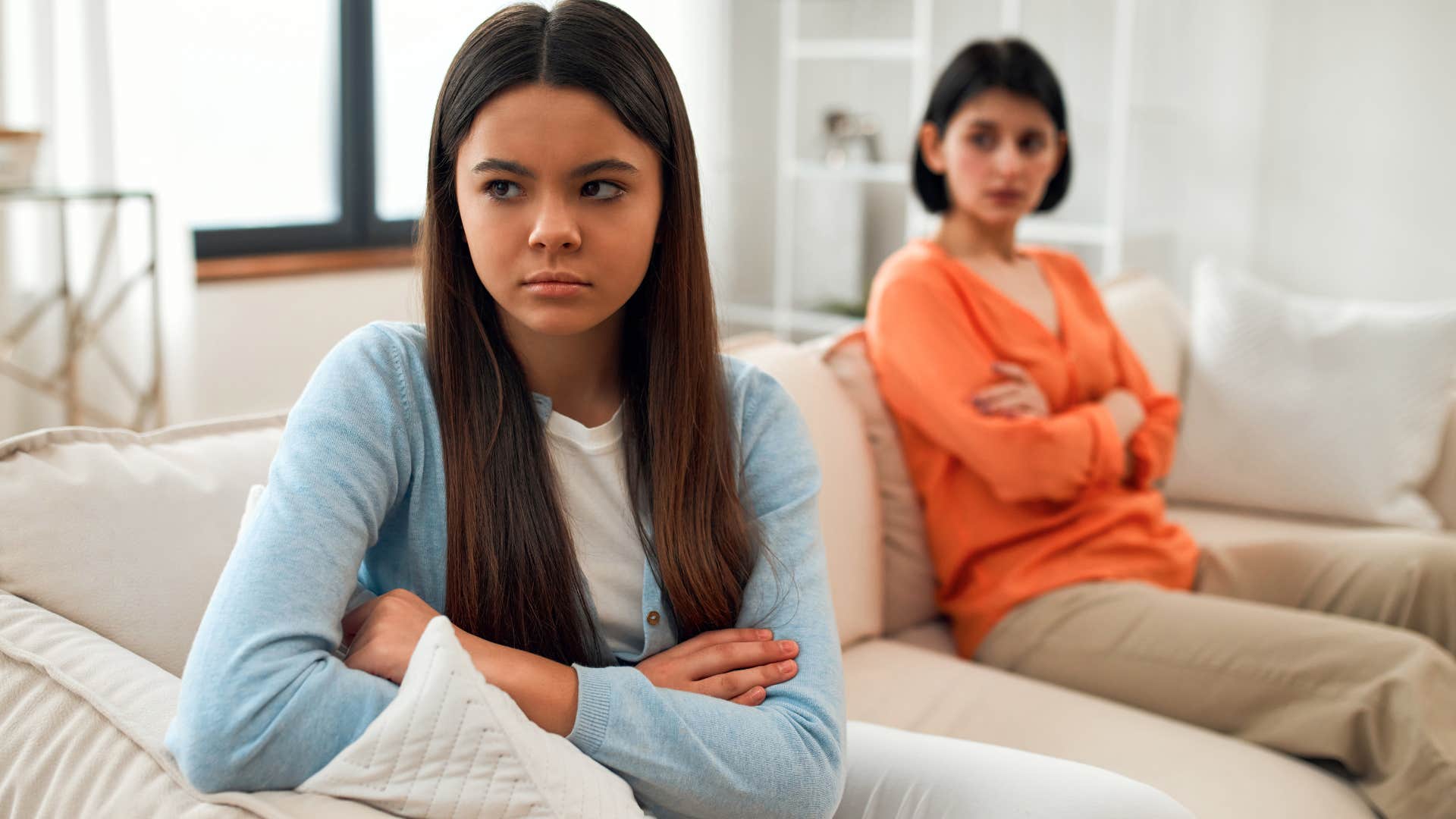 Teenage girl turned away from her upset mother on the couch.