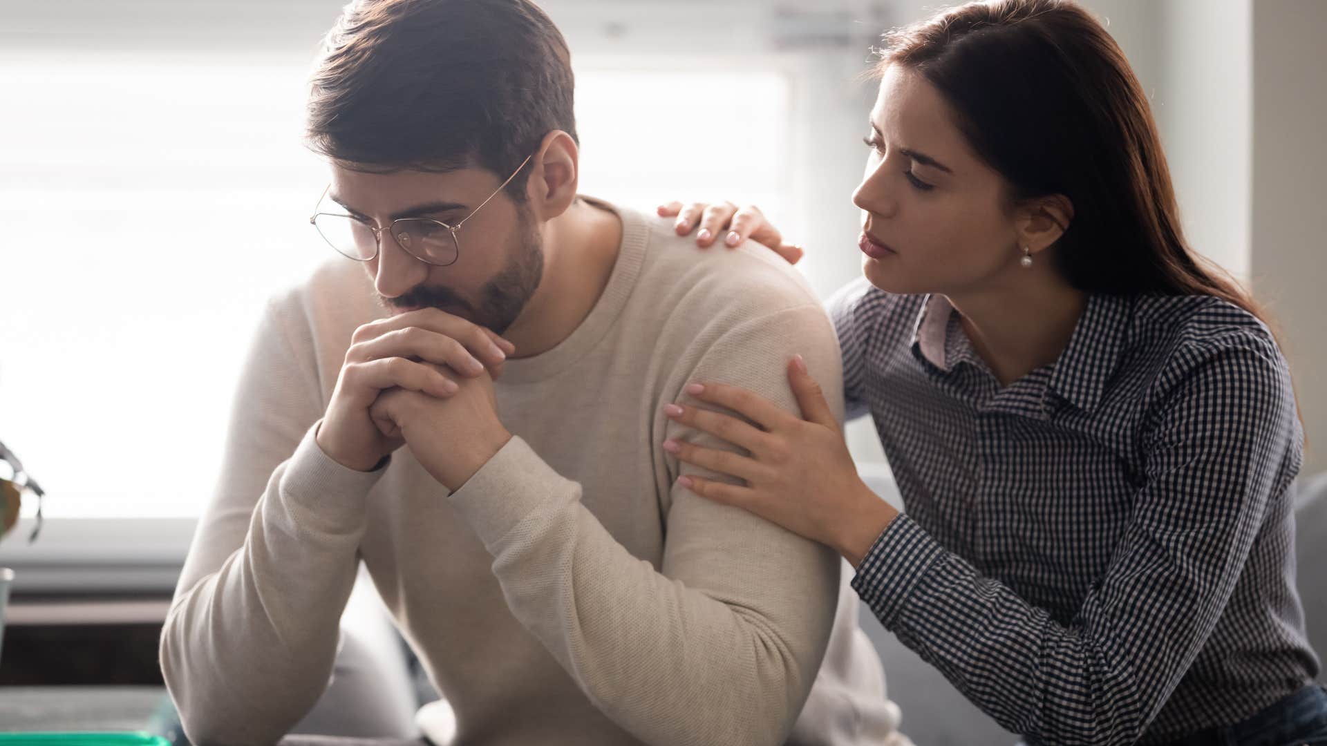 Woman comforting her upset partner on the couch