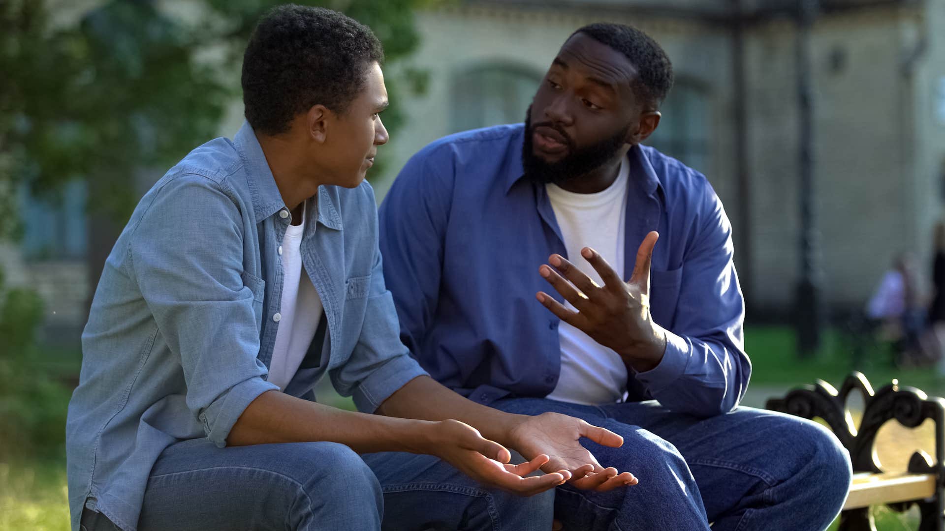 Man talking to his younger brother on a park bench