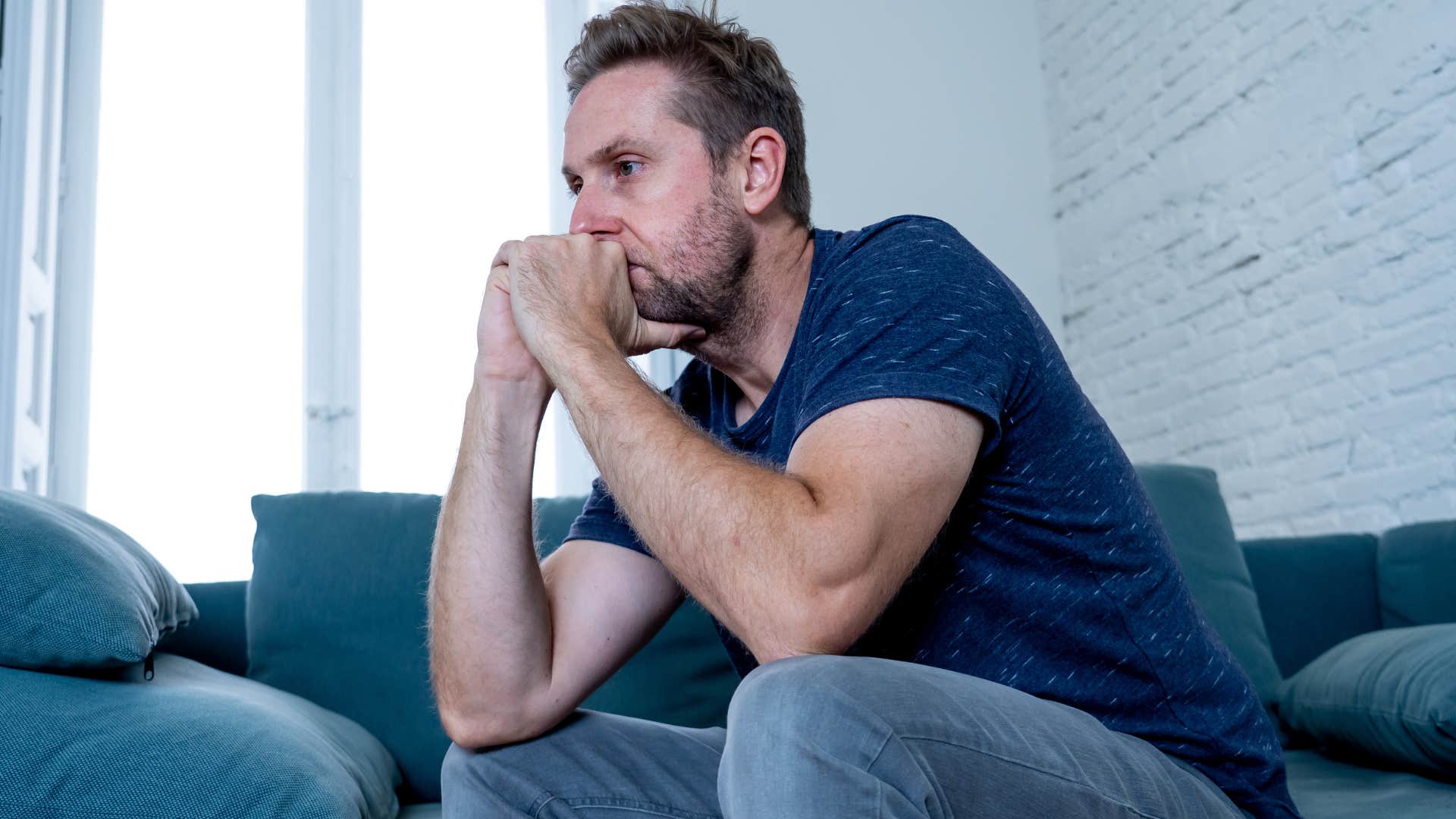 Man looking frustrated sitting on his couch