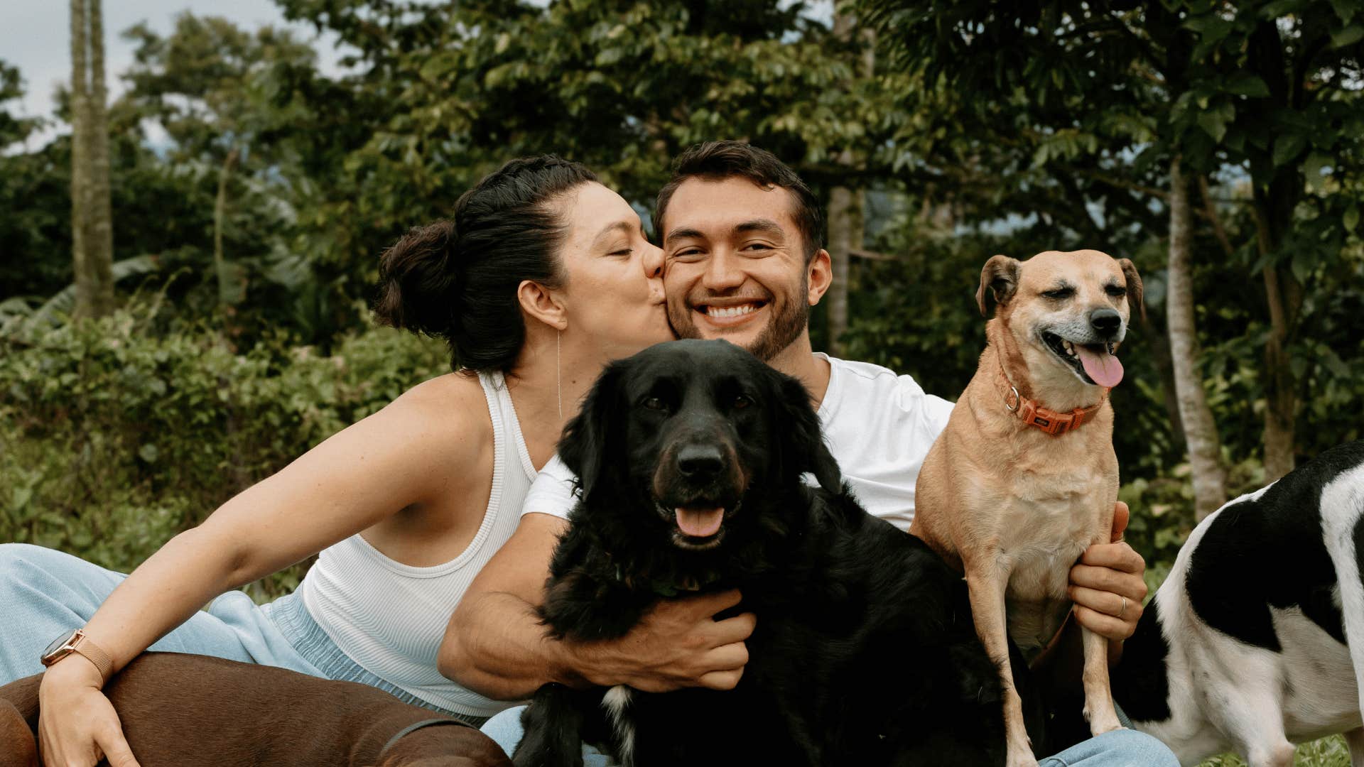 woman kissing man on the cheek with puppies