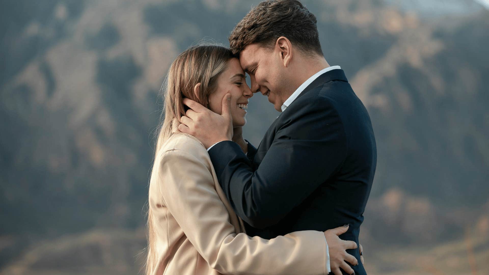 woman hugging man while he holds her face