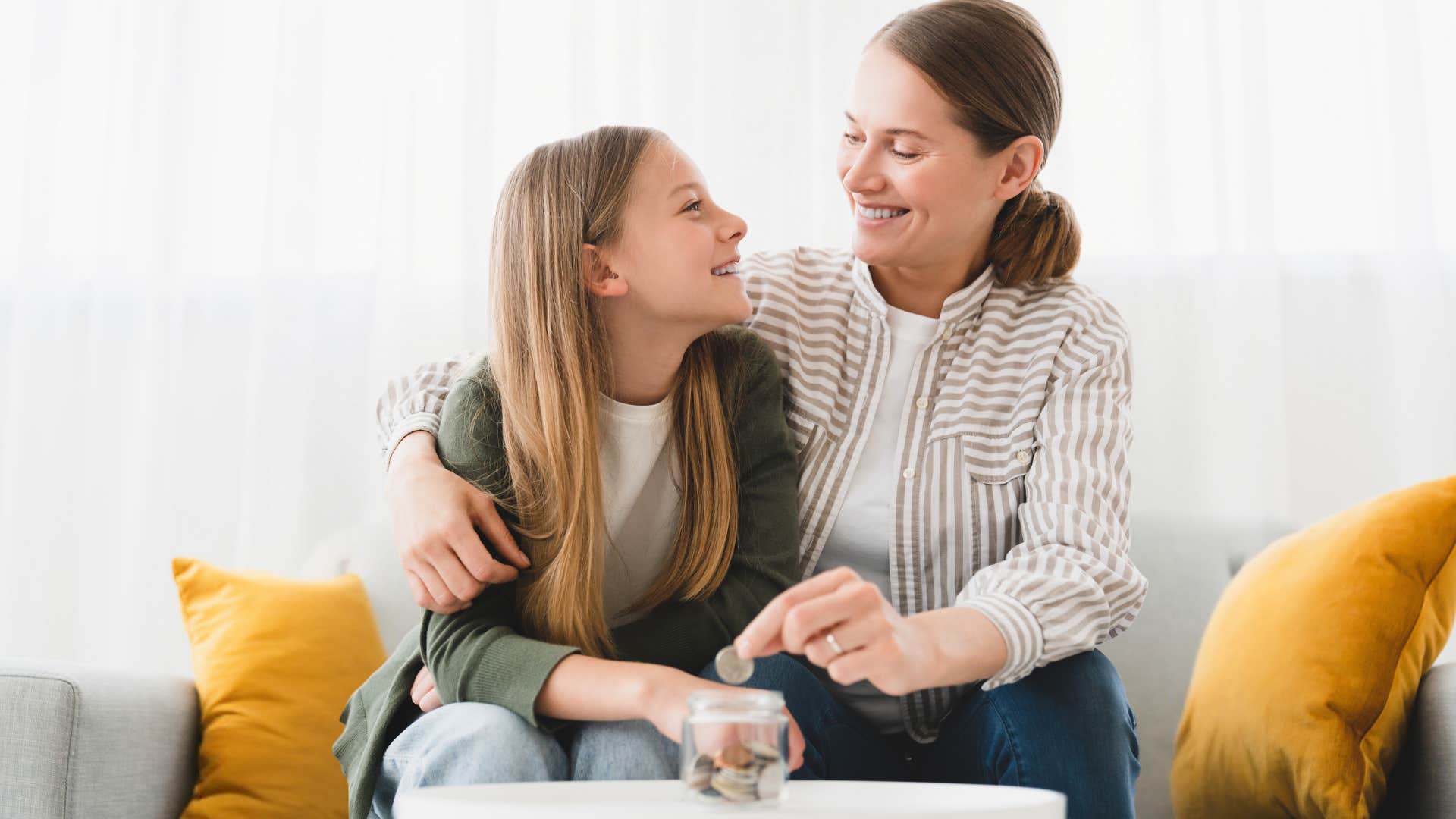 Mom smiling with her teenage daughter putting coins in a container