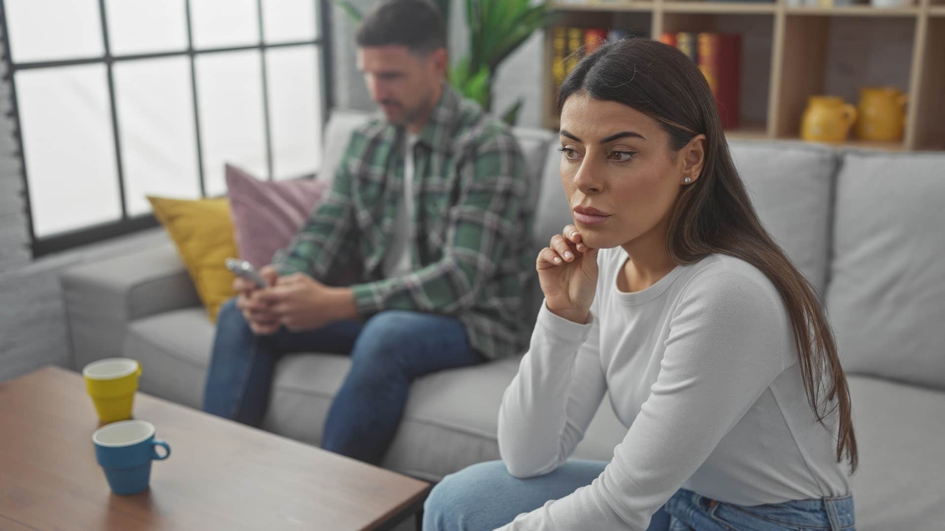 Woman looking away from her boyfriend on his phone