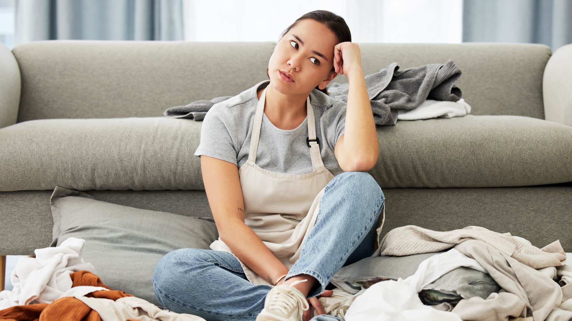 Woman looking upset sitting in a messy room