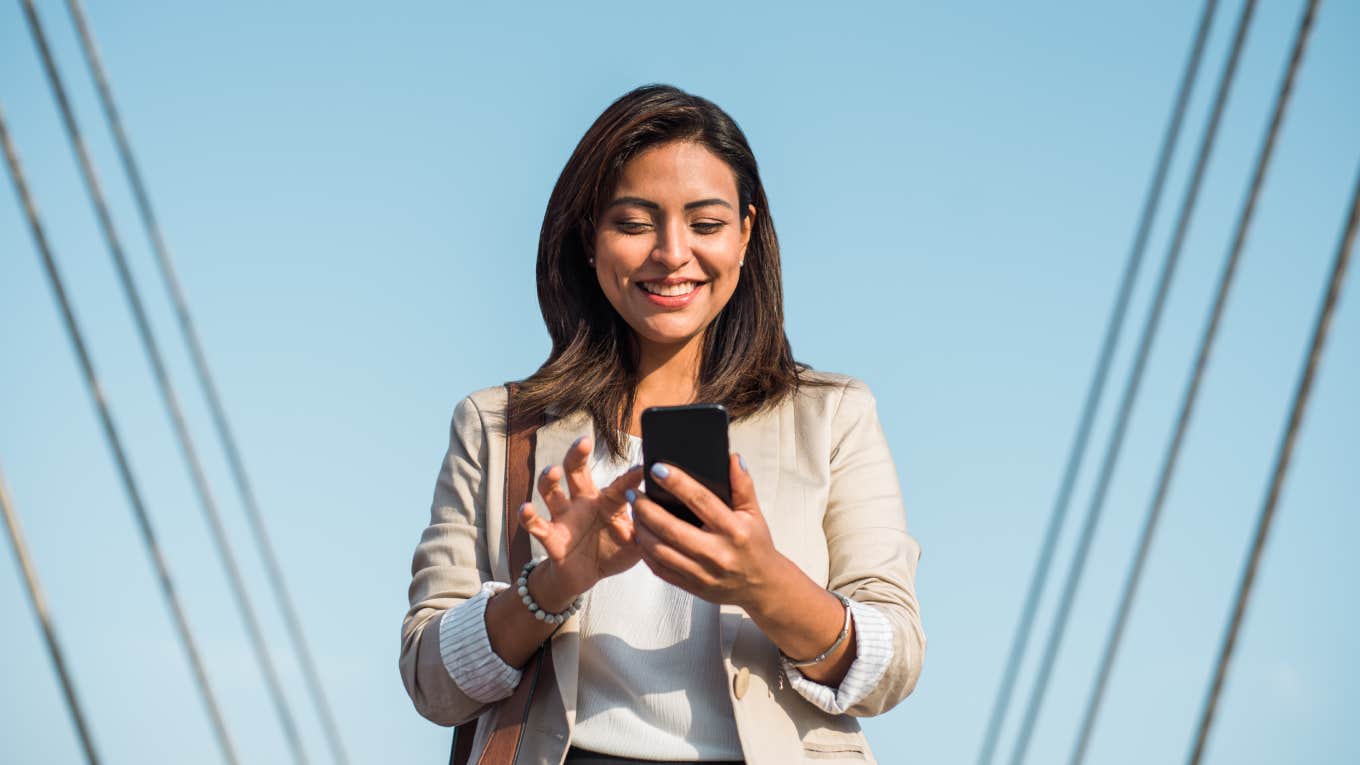 happy elegant young woman stands and uses her phone to type an important message