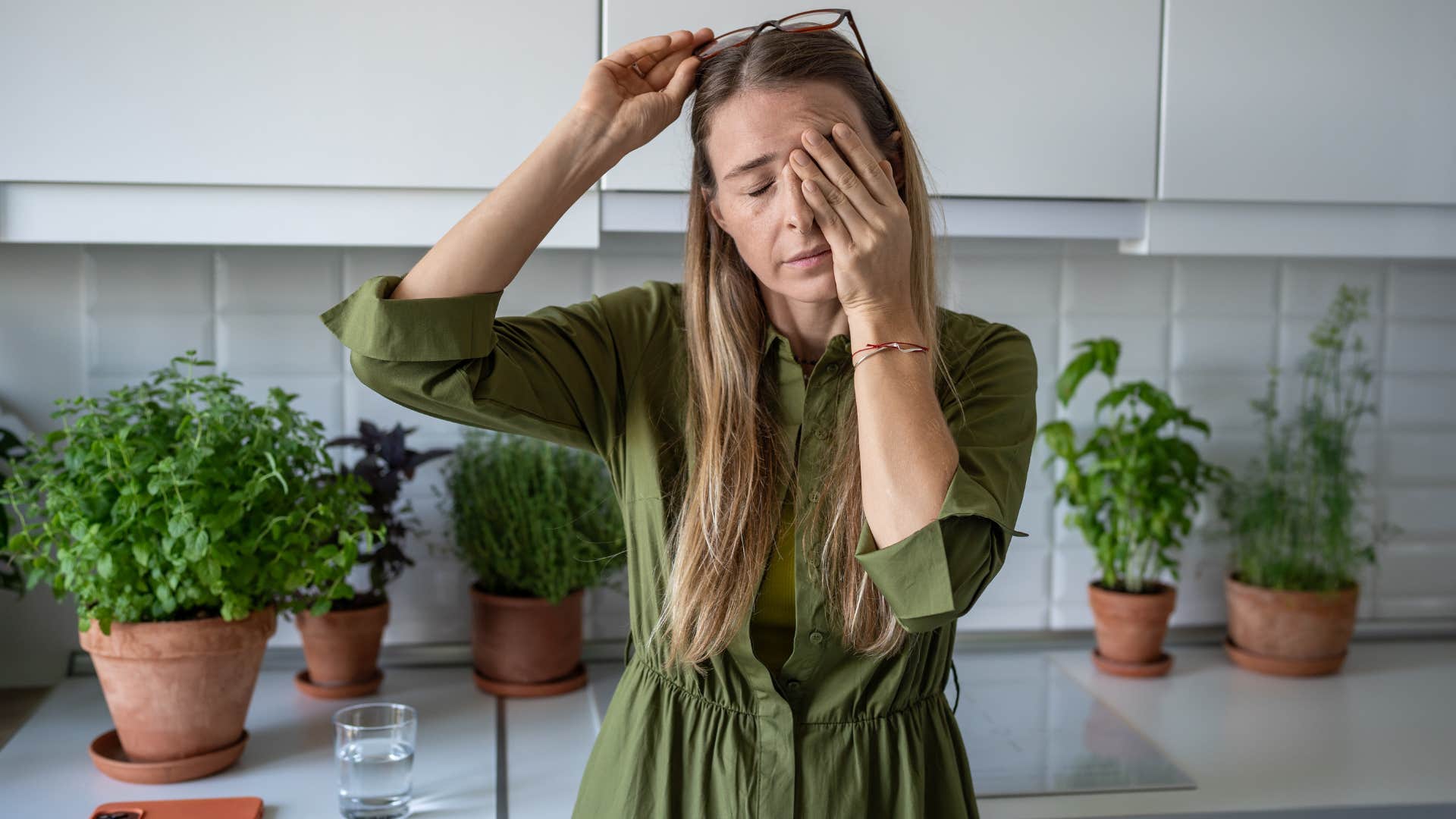 Woman holding her head in her hands looking stressed.