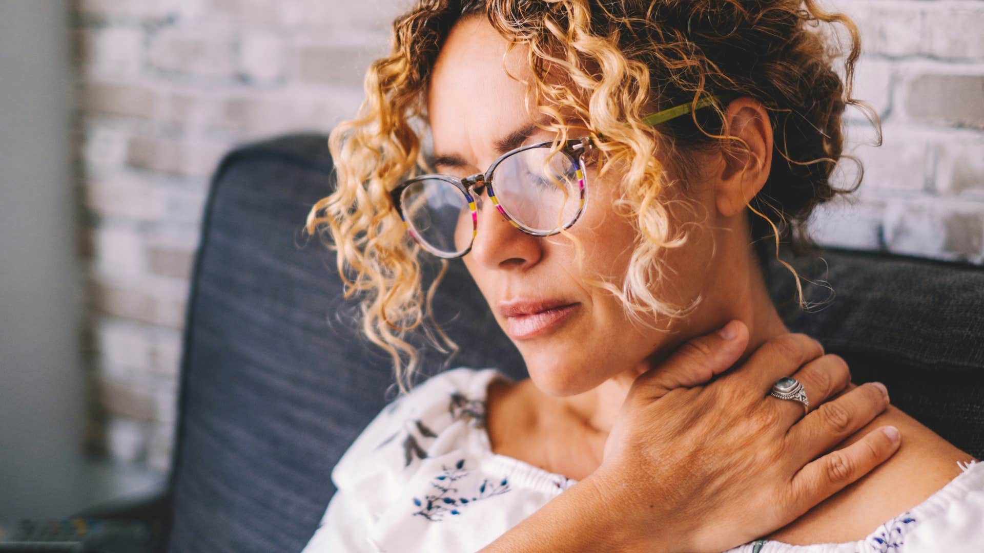 Woman looking upset and holding her neck.