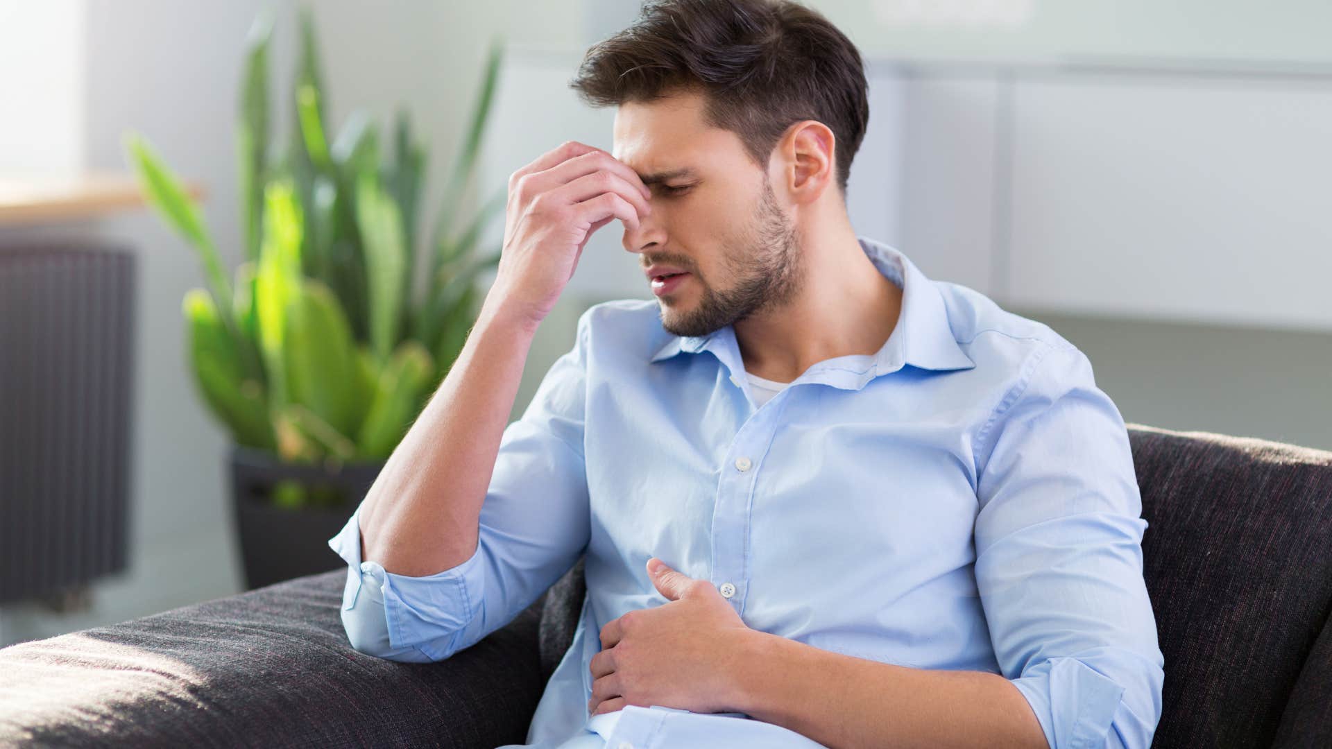 Man holding his stomach and looking upset.