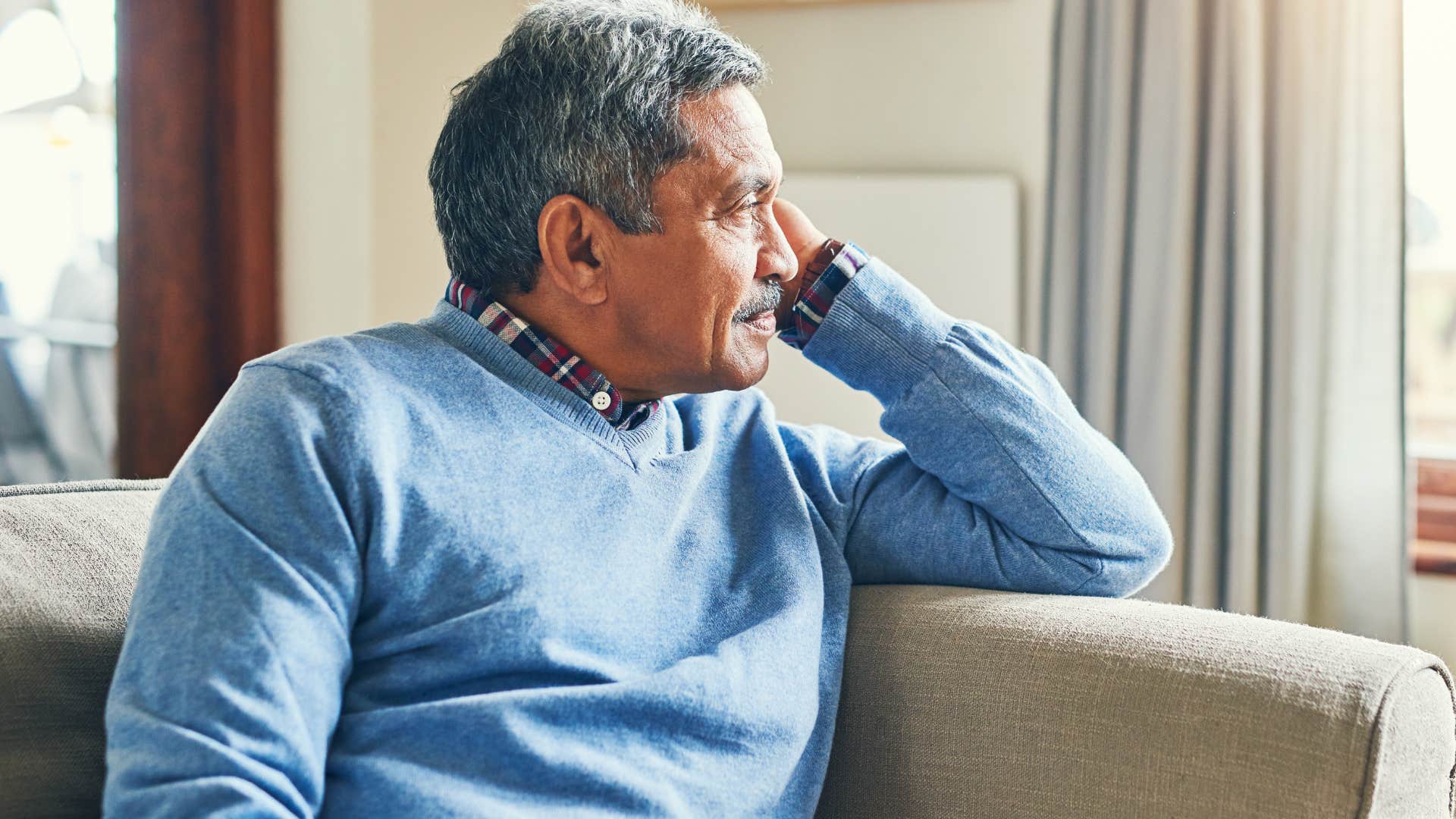 Older man looking upset while staring out a window