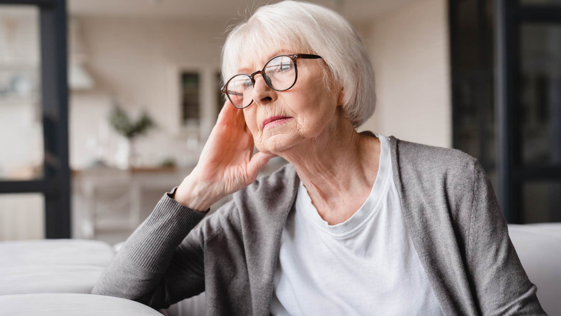 Older woman looking upset staring out a window