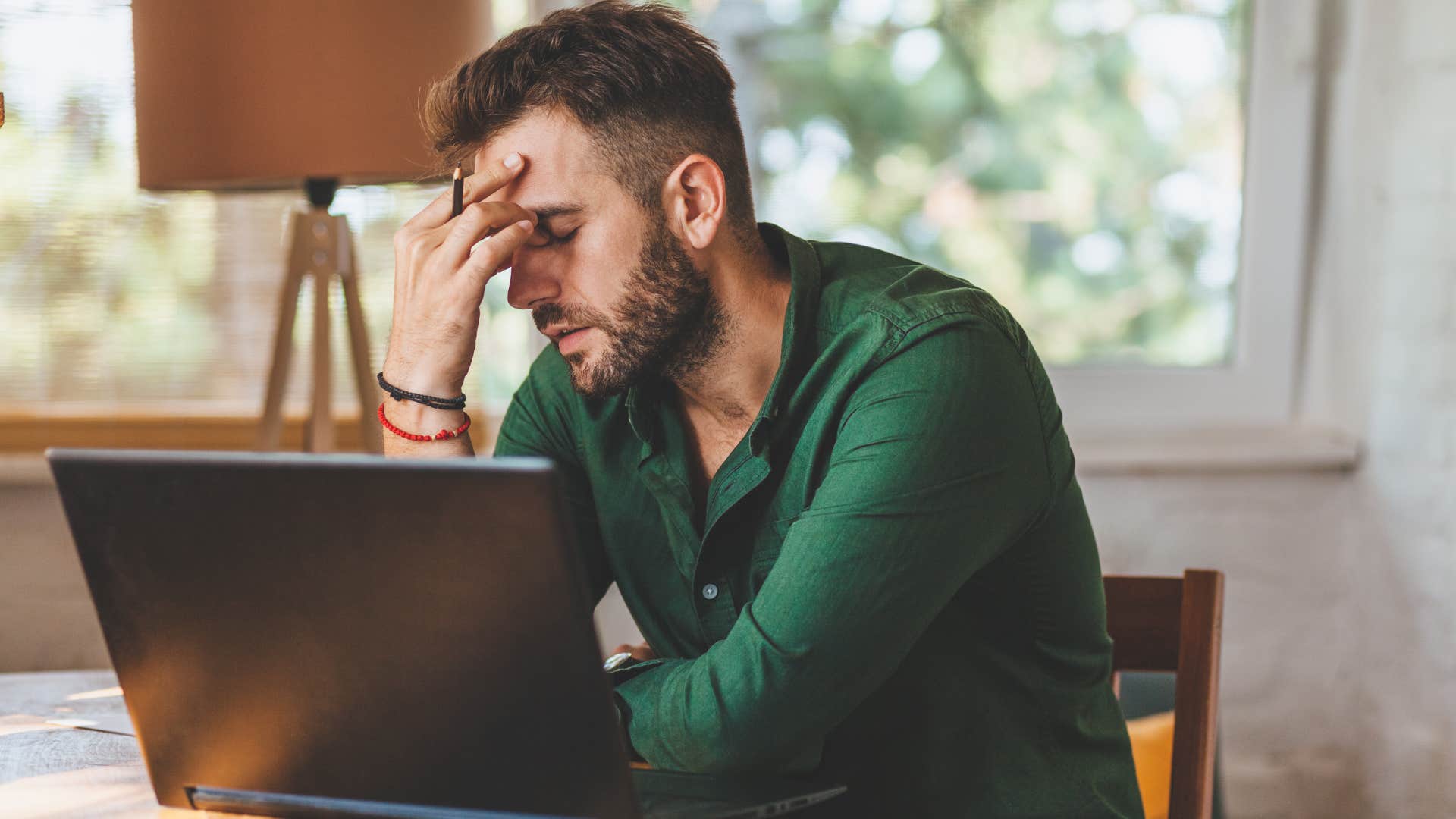 Man looking tired sitting in front of his laptop