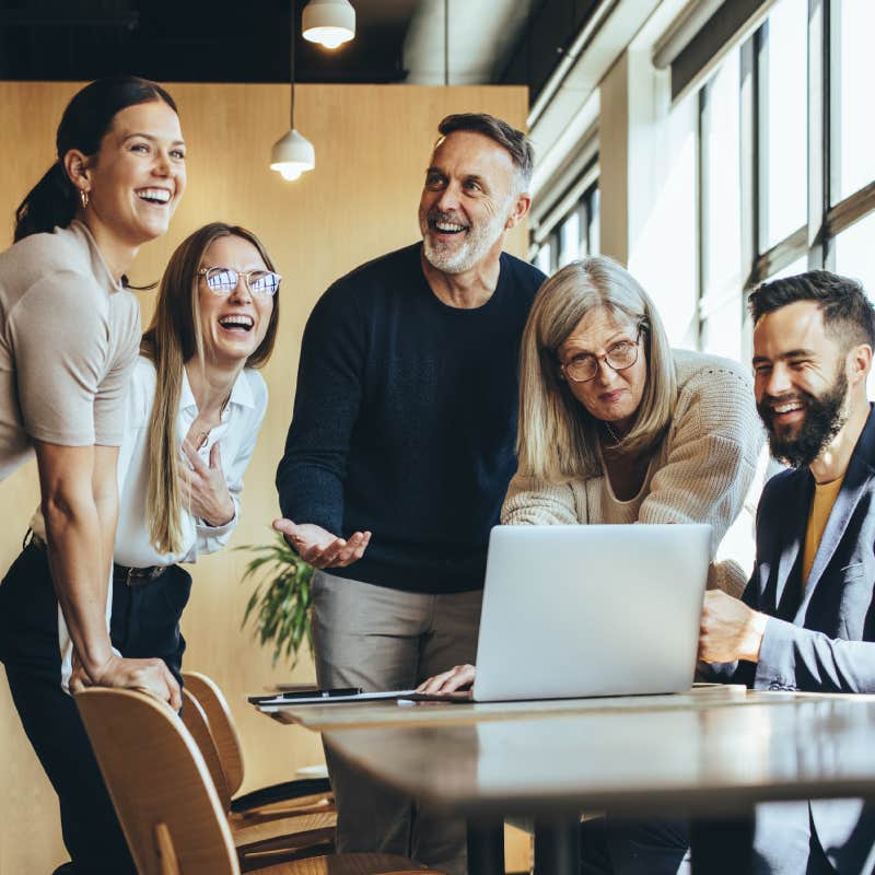 Happy businesspeople laughing while collaborating on a new project in an office