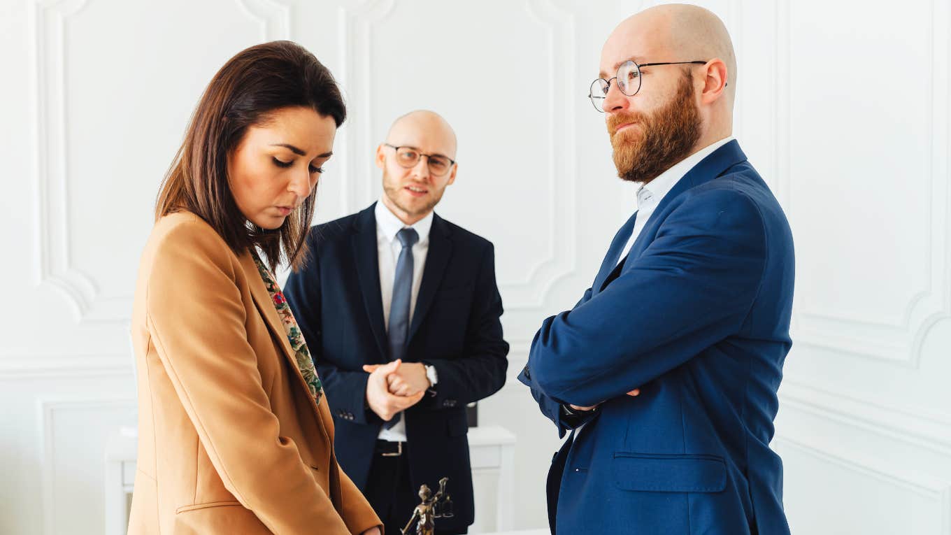 Woman looking down feeling anger, while husband looks satisfied. 