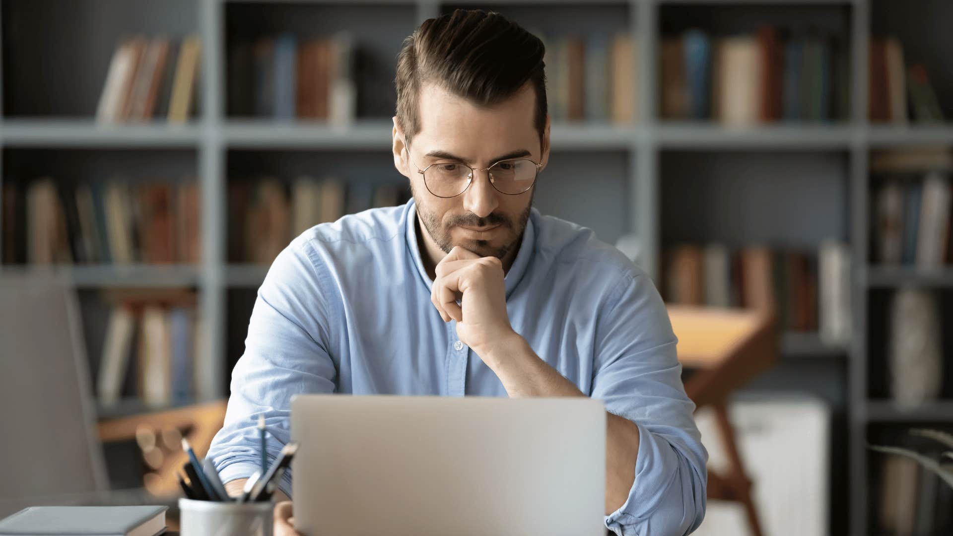 man giving a thoughtful and questioning look while staring at laptop